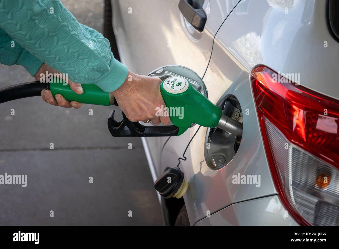 Auffüllen mit teurem Benzin gemischt mit Bioethanol an einer Tankstelle mit einer Fülldüse im Benzintank des Pkw Stockfoto