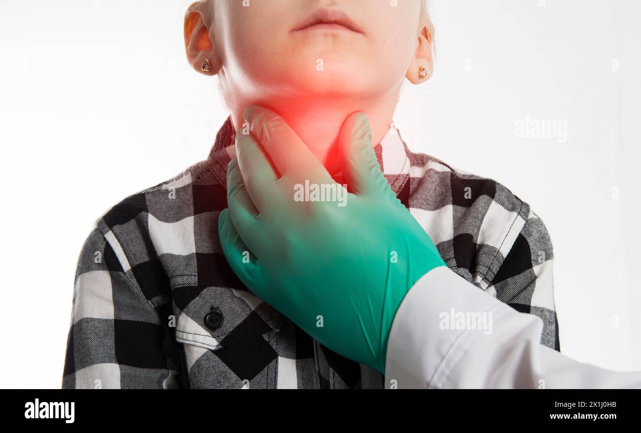 Die Hand eines Endokrinologen palpiert die Schilddrüse eines siebenjährigen Mädchens. Das Konzept der Dysfunktion der Schilddrüsenhormone. Jodmangel, Schilddrüse Stockfoto
