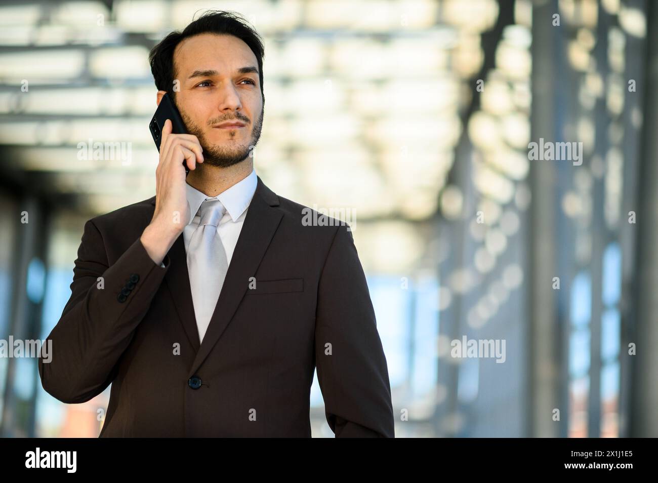 Selbstbewusster junger männlicher Profi, der vor einem Bürogebäude telefoniert Stockfoto