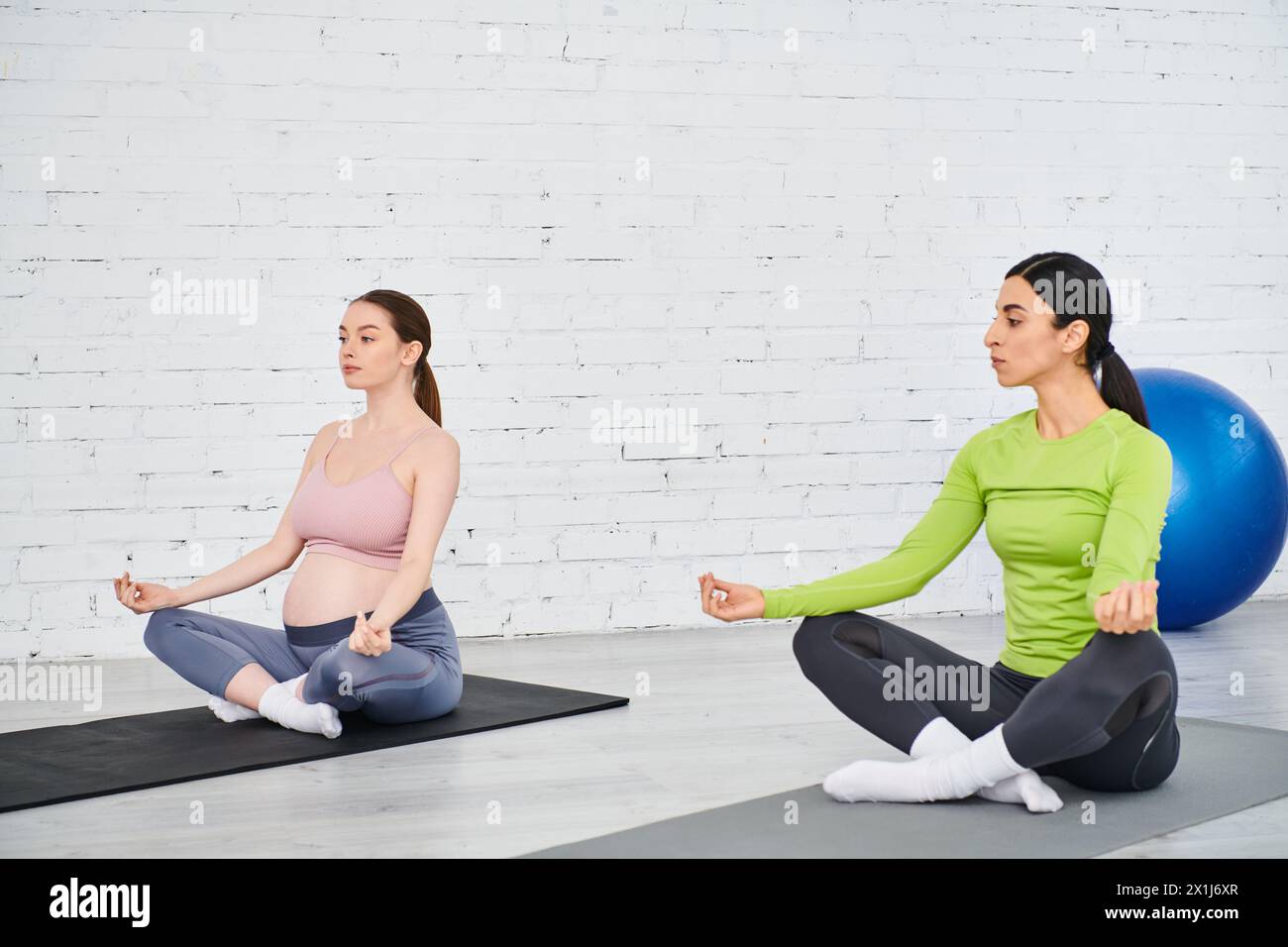 Zwei Frauen sitzen auf Yogamatten und nehmen an einer friedlichen Sitzung Teil. Stockfoto
