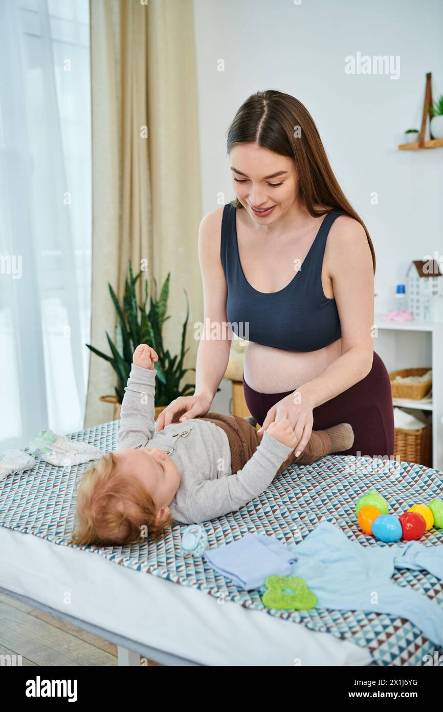 Eine junge, schöne Mutter interagiert spielerisch mit ihrem Baby auf einem gemütlichen Bett, Eltern-Kurse. Stockfoto
