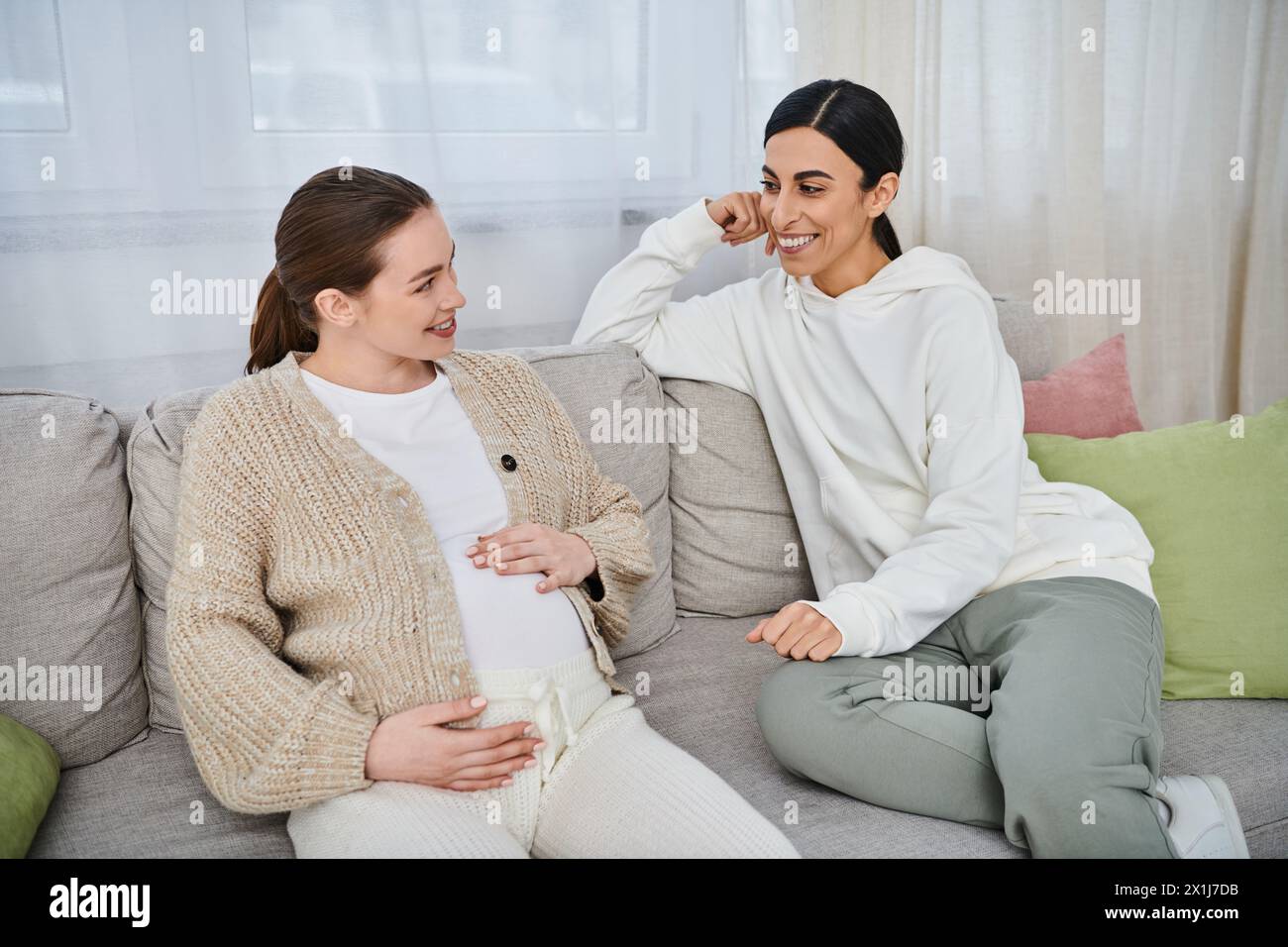 Zwei Frauen, eine schwangere Frau und ihr Trainer, führen während des Elternkurses ein bedeutungsvolles Gespräch auf einer Couch. Stockfoto
