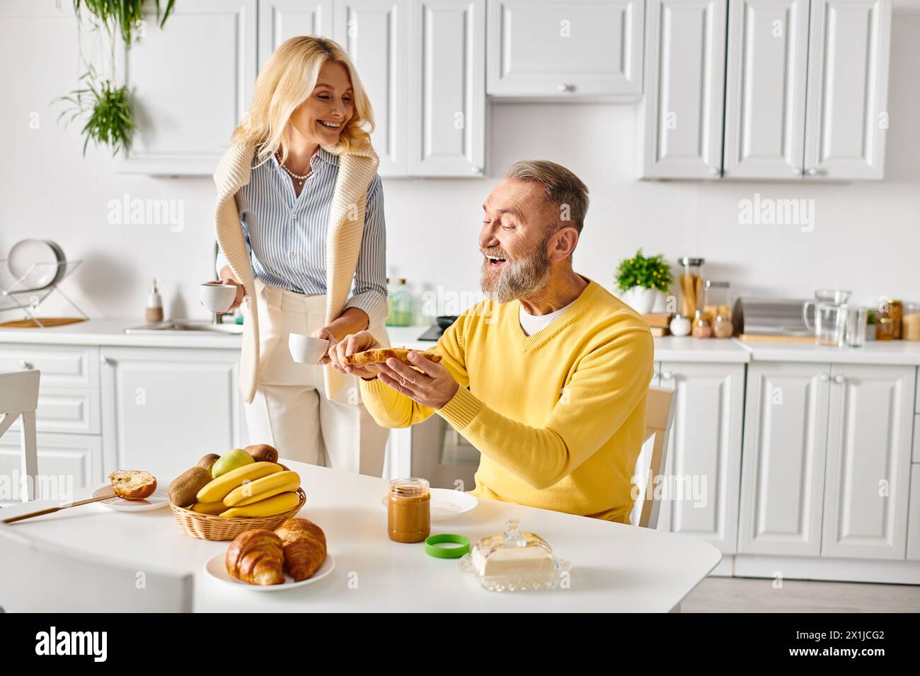 Ein Mann und eine Frau in kuscheliger Homewear sitzen an einem Tisch und teilen einen Moment der Verbindung und Partnerschaft, während sie Zeit miteinander verbringen. Stockfoto