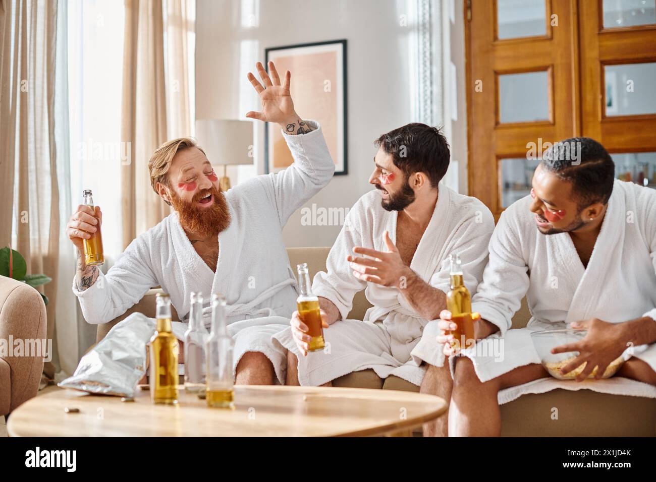 Drei verschiedene Männer in Bademänteln versammeln sich um einen Tisch und genießen sich bei einem gemeinsamen Drink. Stockfoto