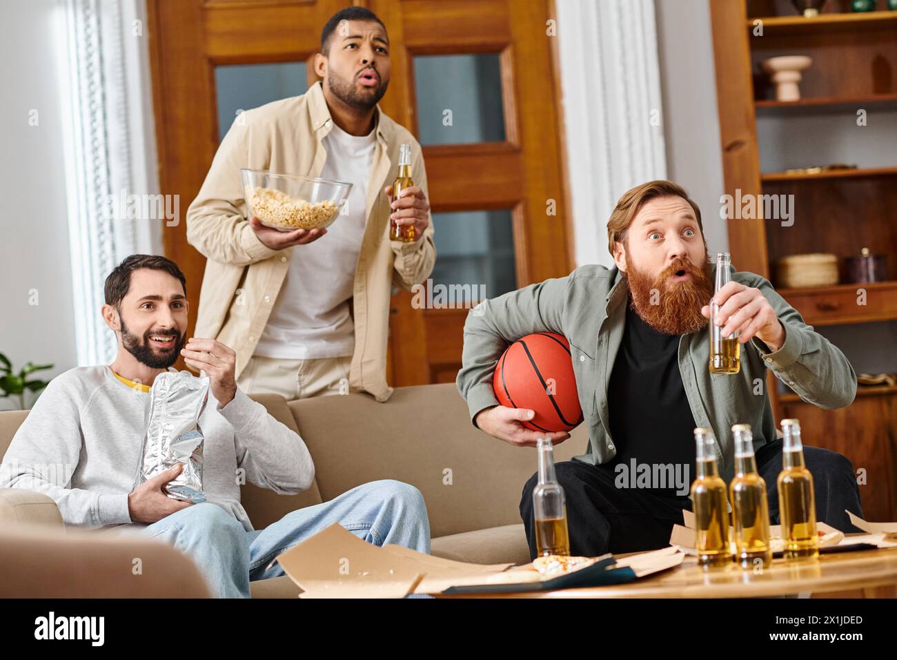 Drei gutaussehende Männer in lässiger Kleidung teilen sich Drinks, lachen und genießen eine tolle Zeit zu Hause. Stockfoto