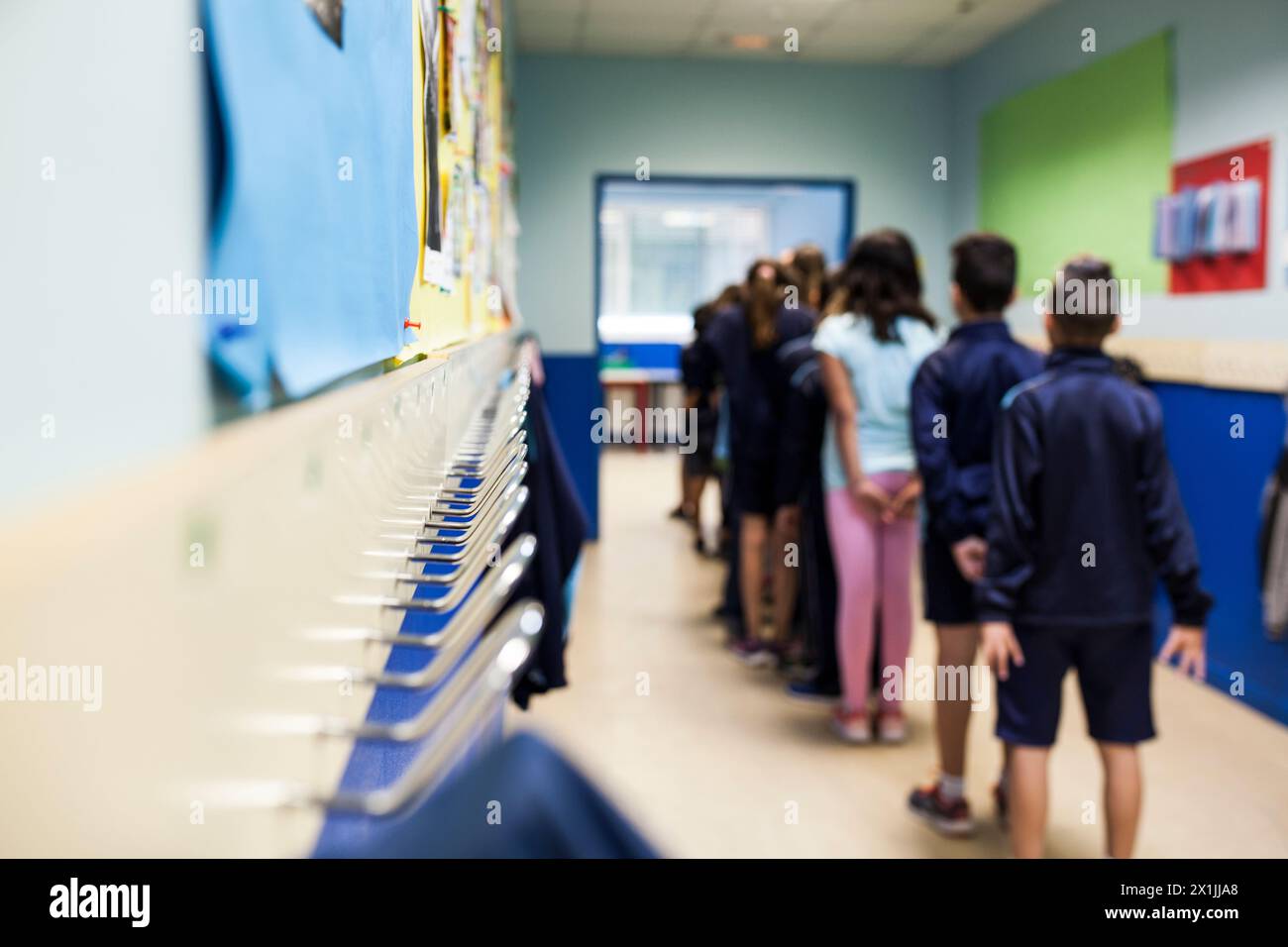 Eine Reihe von Schülern auf dem Rücken in einer Schulhalle vor Garderobenständern Stockfoto