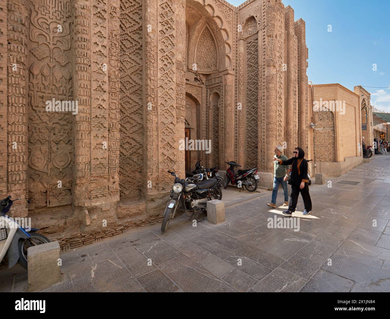 Die Menschen laufen in einer engen Straße am Jorjir-Tor, dem einzigen verbliebenen Teil der Jorjir-Moschee aus dem 10. Jahrhundert in Isfahan, Iran. Stockfoto