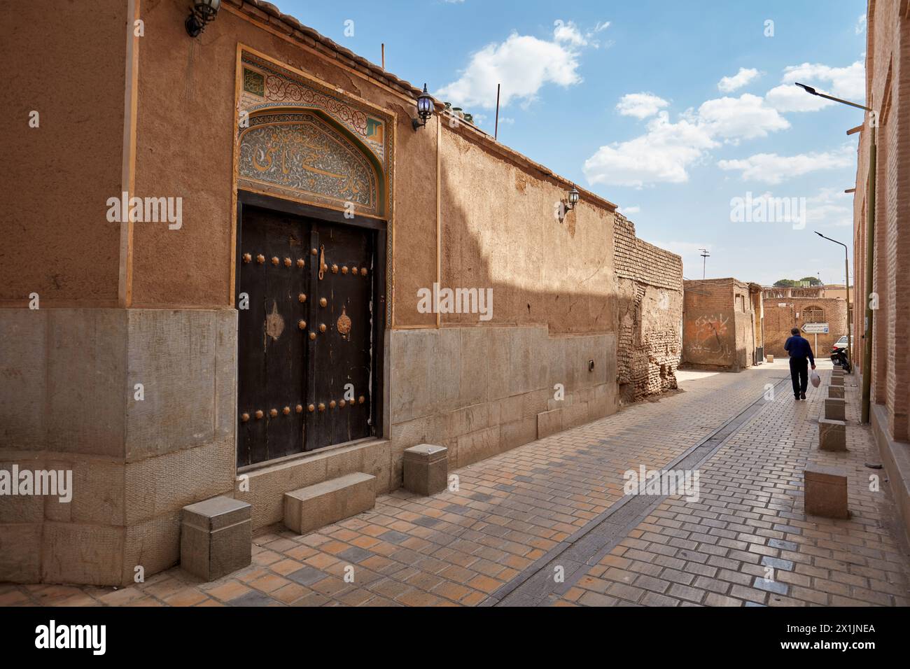 Eingangstür eines traditionellen iranischen Hauses gegenüber einer engen Kopfsteinpflasterstraße im historischen Zentrum von Isfahan, Iran. Stockfoto