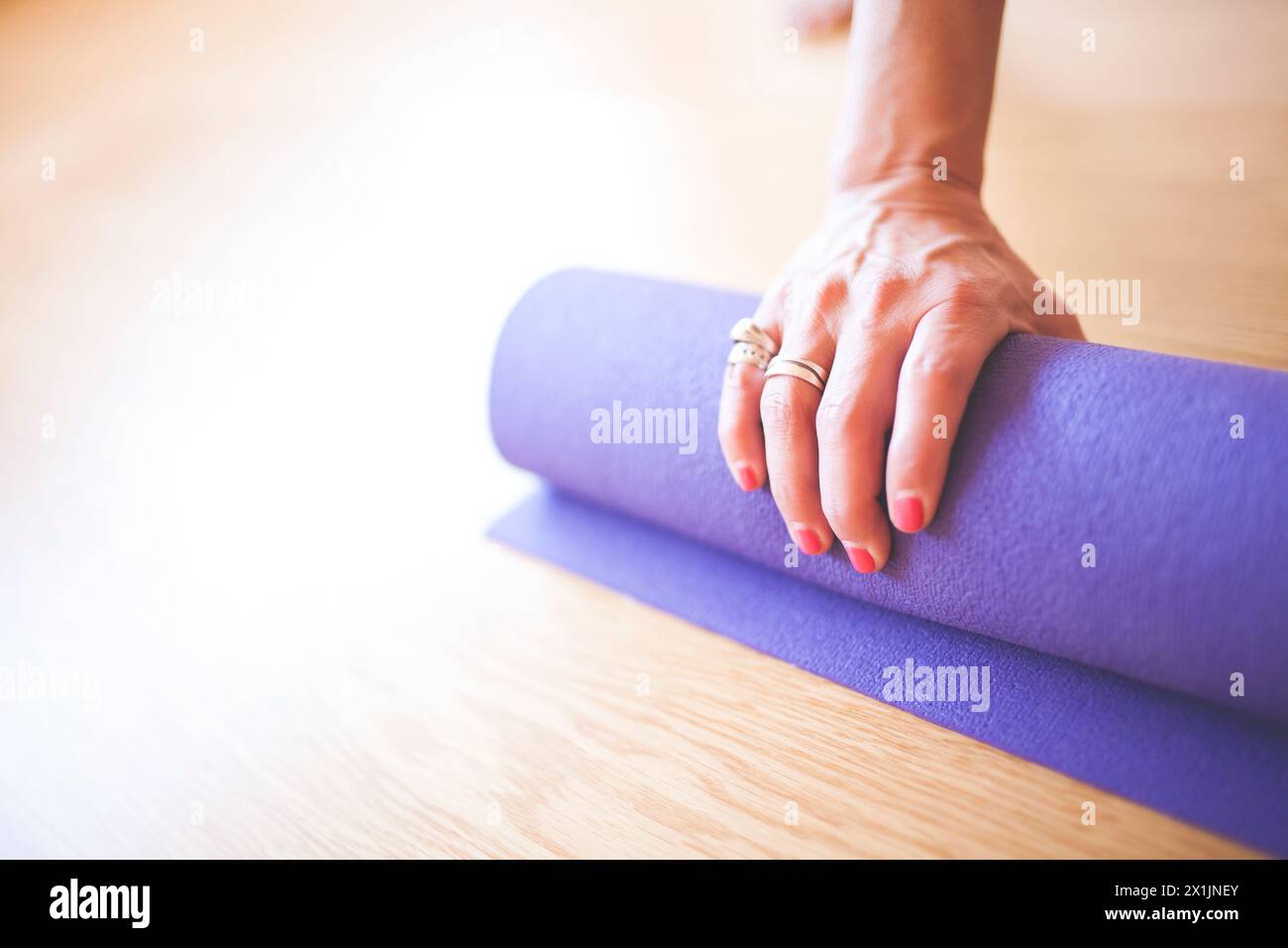 Unerkennbare Frau Yogi rollt die Matte mit einer Hand Stockfoto