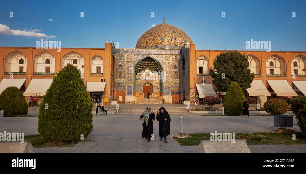 Iranische Frauen in schwarzen Chadors gehen an der Lotfollah-Moschee auf dem Naqsh-e Jahan-Platz. Isfahan, Iran. Stockfoto