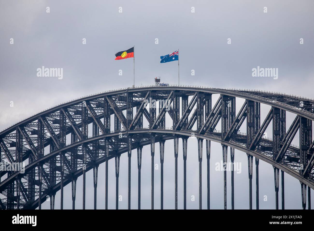 Nahaufnahme der Sydney Harbour Bridge, Brückenkletterer standen auf dem Gipfel unter der australischen Nationalflagge und der Flagge der Aborigines, Sydney, 2024 Stockfoto