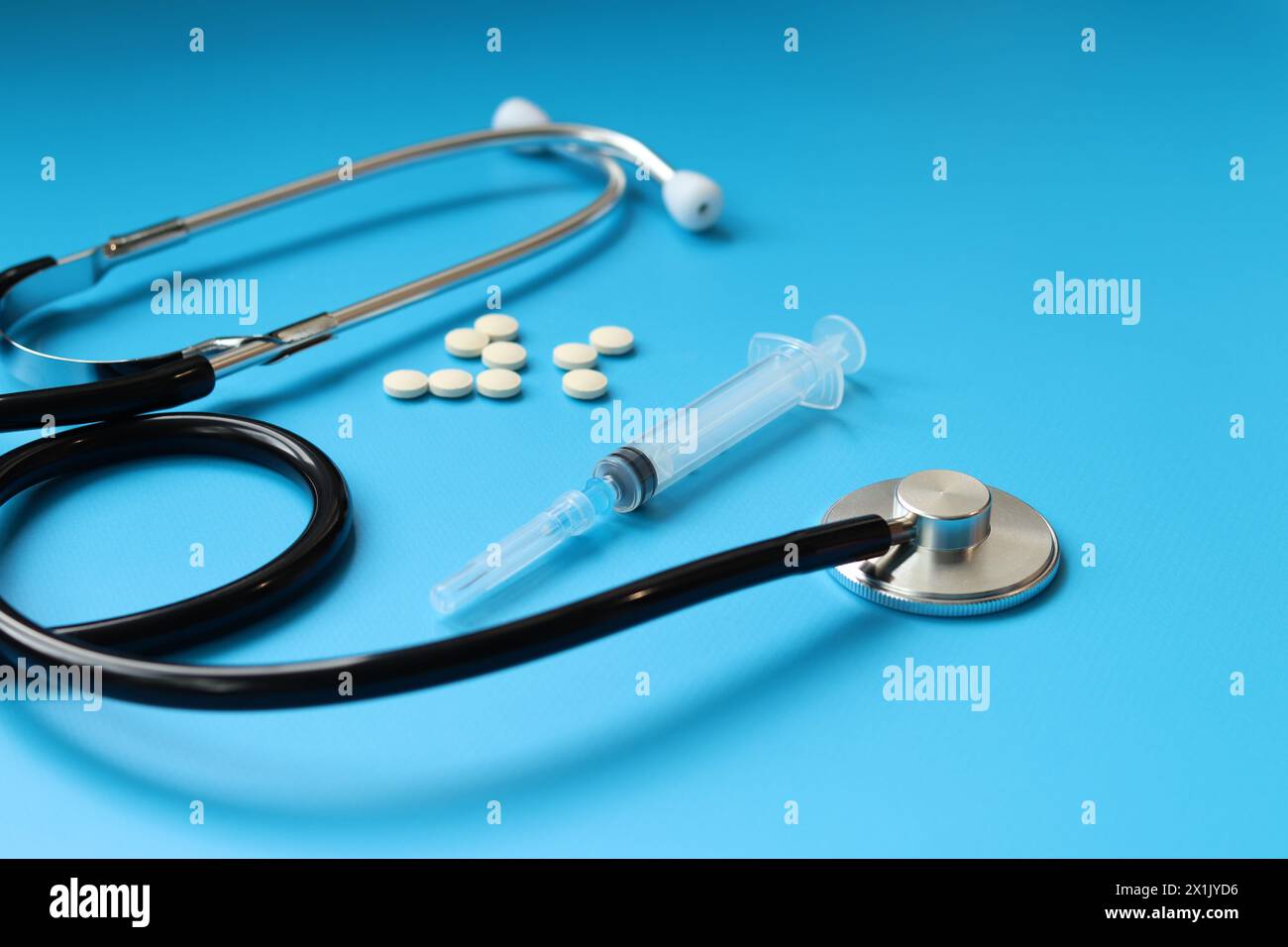 Stethoskop, Pillen und Spritze auf blauem Hintergrund, selektiver Fokus. Kardiologie und Gesundheitskonzept. Auskultationsgerät. Medizinisches Versorgungskonzept. Medi Stockfoto