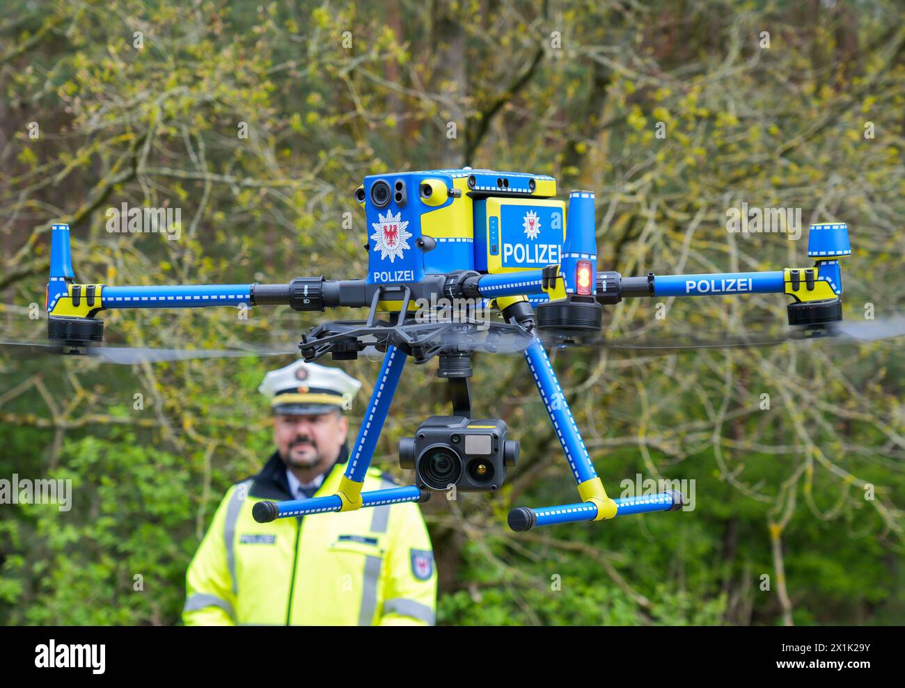 Walsleben, Deutschland. April 2024. Mathias Funk, Leiter Verkehrsangelegenheiten und Verkehrsunfallprävention im Polizeipräsidium Brandenburg, beobachtet eine Polizeidrohne beim Abheben des Parkplatzes Rosskower Heide auf der Autobahn A24, mit der die Entfernung fahrender LKWs gemessen werden kann. Neben der Distanzmessung wurden bei einem bundesweiten Inspektionstag auch die technischen Einstellungen und der Zustand von Lkw und Bussen überprüft. Quelle: Soeren Stache/dpa/Alamy Live News Stockfoto