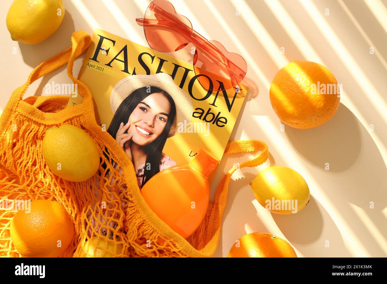 Schnur Tasche mit frischem Obst, Modemagazin und Strandaccessoires auf beigefarbenem Hintergrund, flache Lay Stockfoto