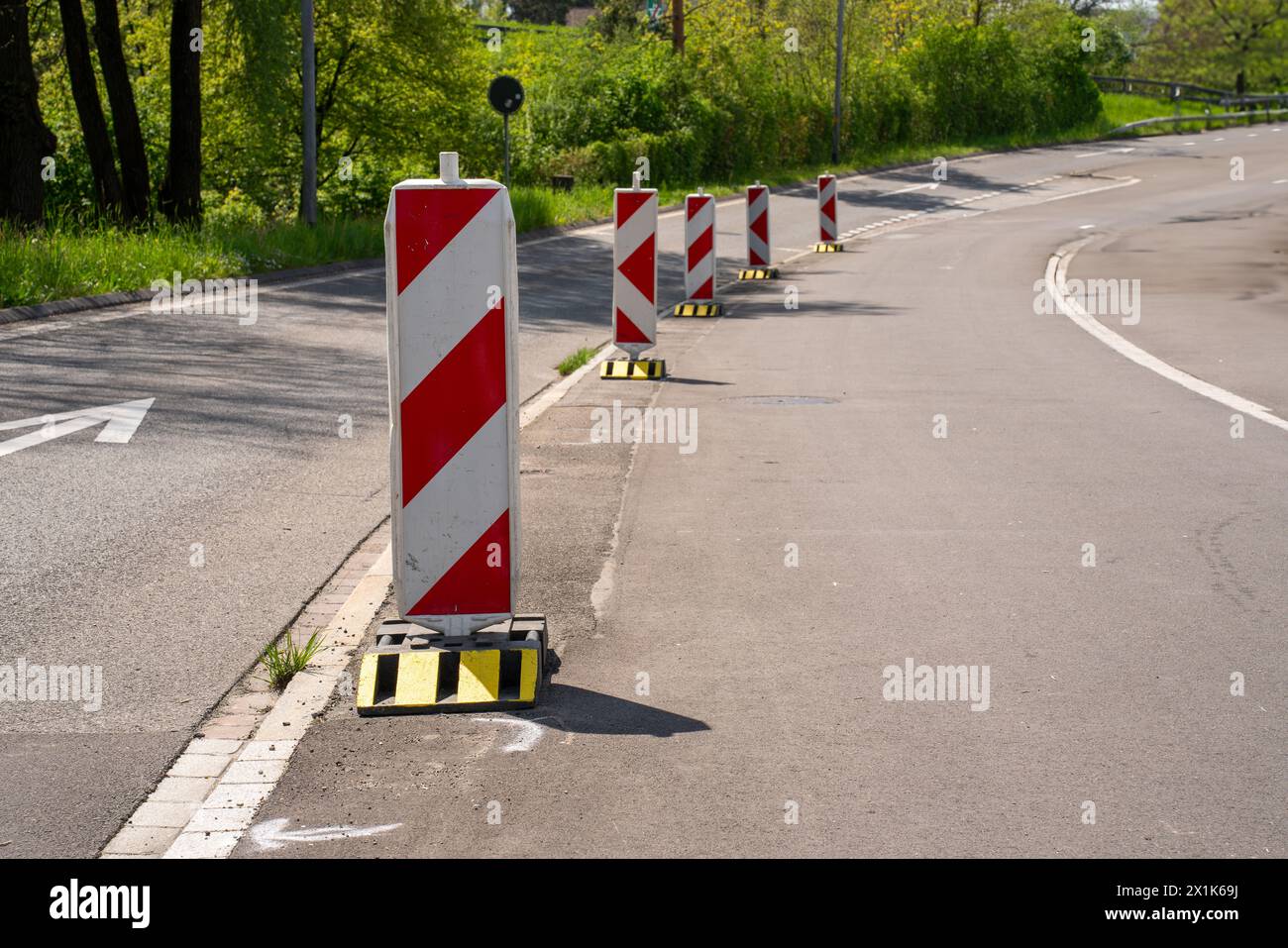 Warnkähne in Rot und Gelb am Straßenrand signalisieren einen Umweg auf einer Baustelle. Stockfoto