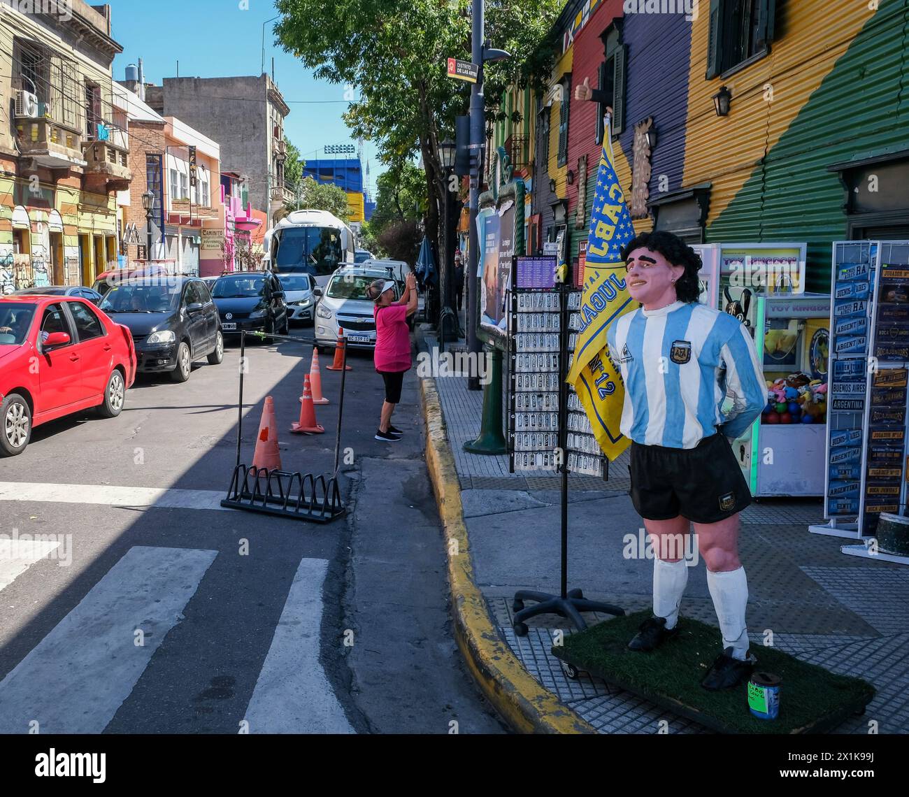 La Boca, Buenos Aires, Argentinien - die Figur der Fußballlegende Diego Maradona begrüßt Touristen vor einem Geschäft. Auf der Rückseite, La Bombonera Stad Stockfoto