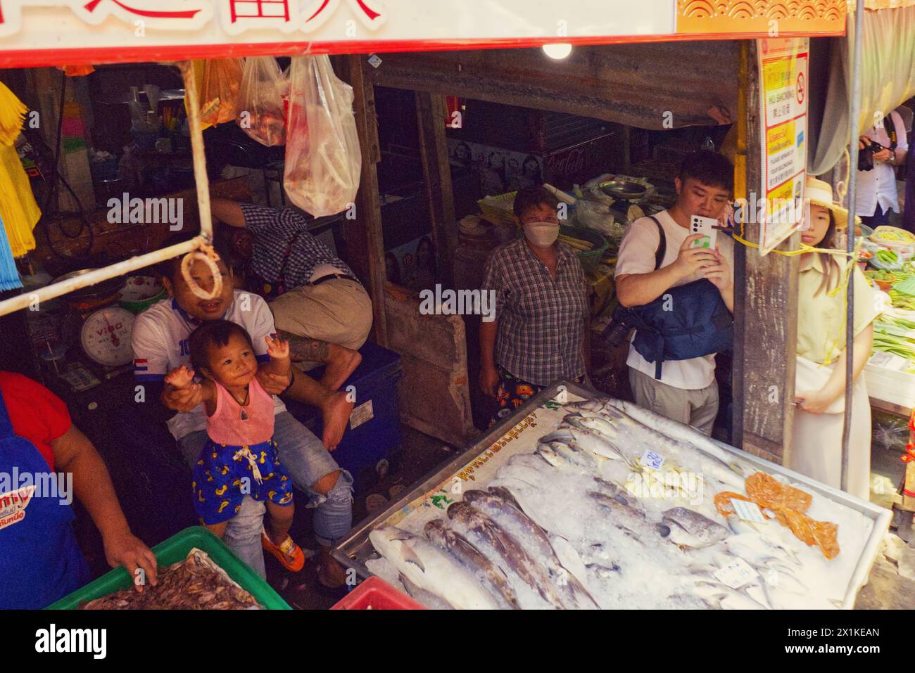 Maeklong, Thailand - aus der Kutsche heraus, wie der Mann den Zug, der am Fischhändler vorbeifährt, auf dem Bahnmarkt ganz in der Nähe der Verkaufsstände erfasst Stockfoto