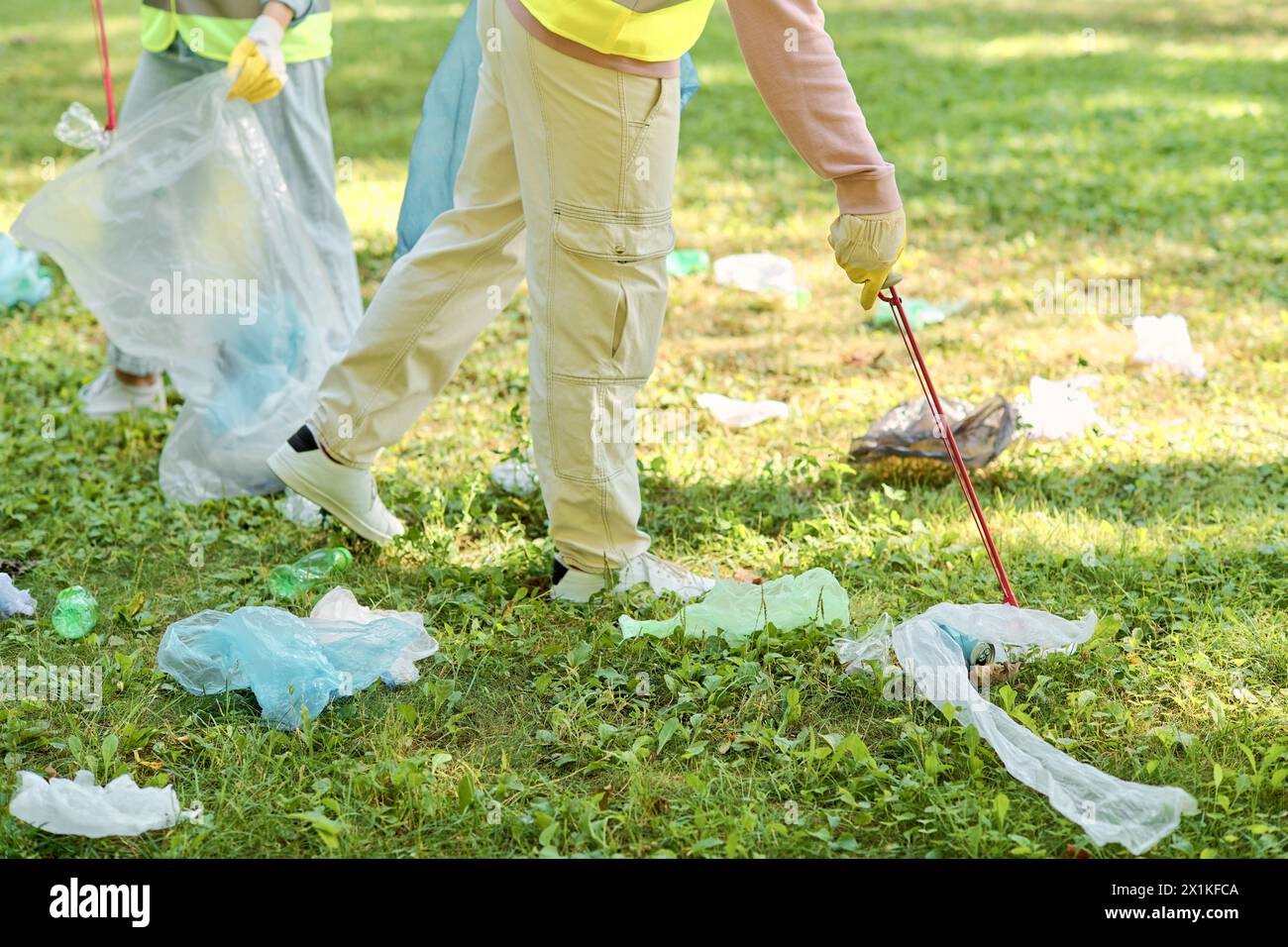 Ein vielseitiges Paar steht auf einem lebendigen grünen Feld, umgeben von üppiger Umgebung, verkörpert Liebe und reinigt aktiv den Park. Stockfoto