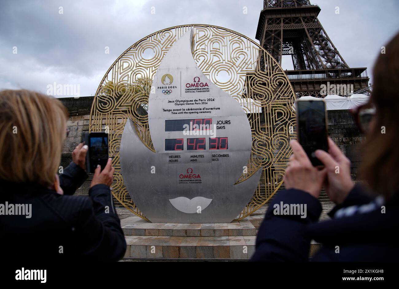 Tourists picture the countdown clock reading 100 days before the Paris 2024 Olympic Games opening ceremony, Wednesday, April 17, 2024 in Paris. The Paris 2024 Olympic Games will run from July 26 to Aug. 11. (AP Photo/Christophe Ena) Stockfoto