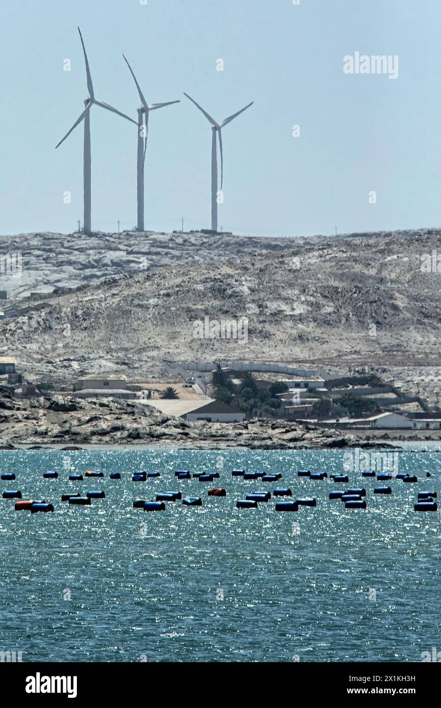 Drei Windturmtürme auf dem felsigen Hügel, oberhalb der Stadt und der Austernfarm, am Meer in Luderitz. Stockfoto