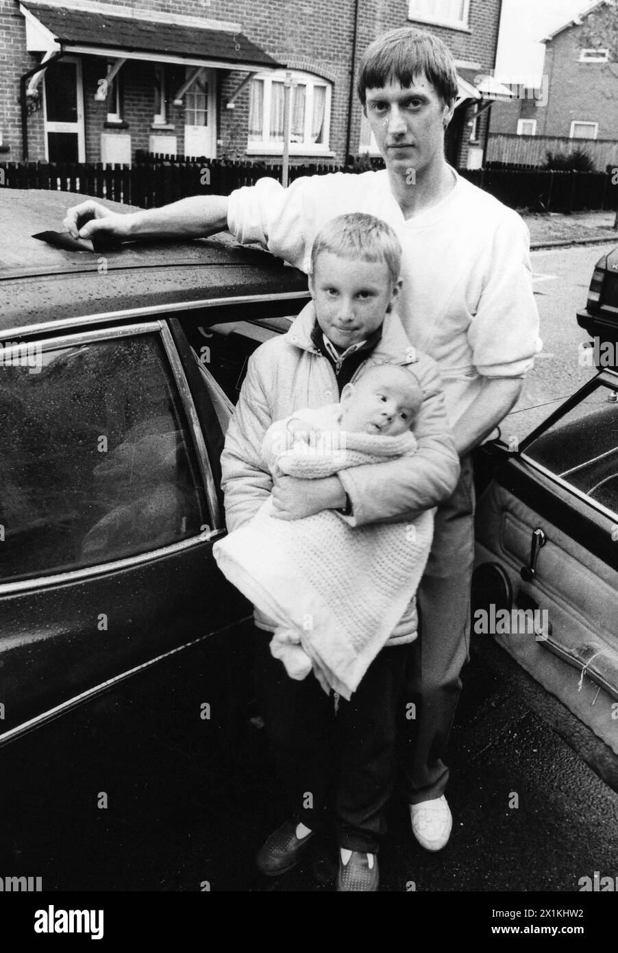 DAVID LEWIS AUS EASTLEIGH MIT SEINEN KINDERN, DAMIEN UND BABY JAMES NEBEN IHREM AUTO, NACHDEM EIN TEIL EINES FLUGZEUGS VOM HIMMEL FIEL UND AUF DEM AUTODACH LANDETE. OKT. 1988 PIC MIKE WALKER 1988 Stockfoto