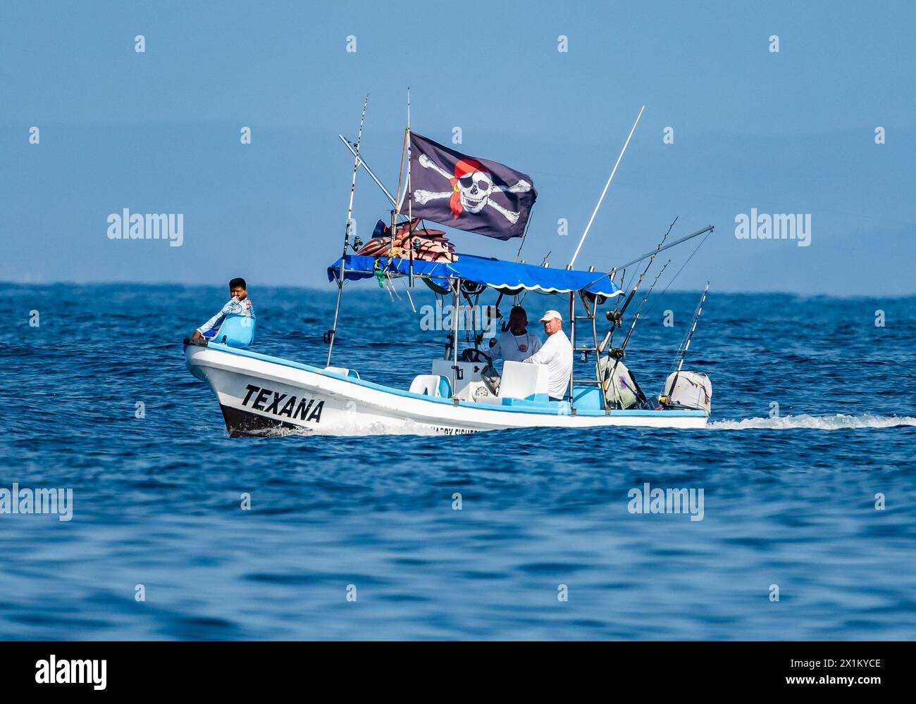 Ein kleines Fischerboot mit Piratenflagge vor der Küste von Oaxaca, Mexiko. Stockfoto