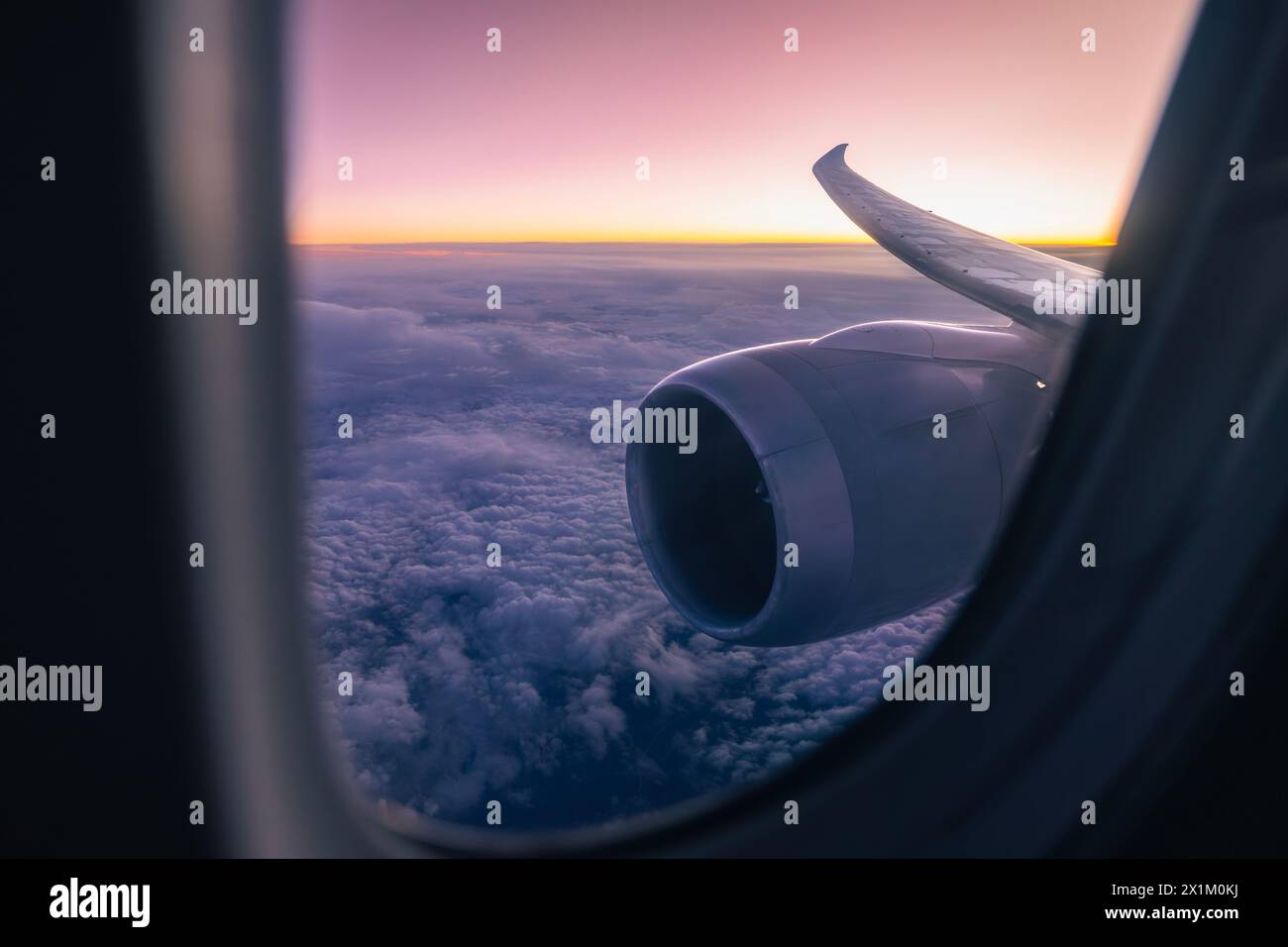 Wunderschöner Blick vom Flugzeugfenster über den Düsenmotor und den Flügel. Flugzeuge fliegen hoch über Wolken während der Dämmerung.Themen Luftfahrt, Reise und Verbindung. Stockfoto