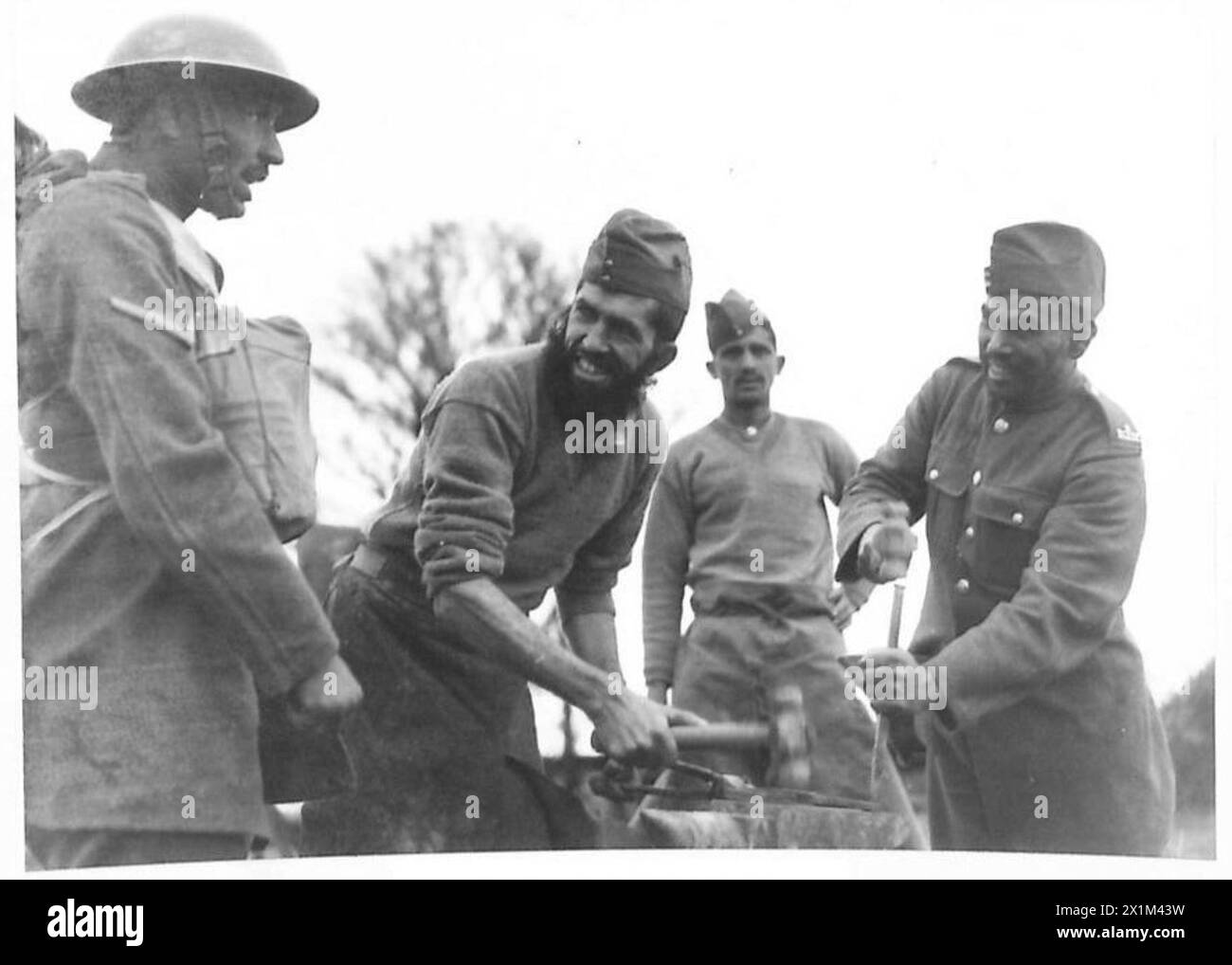 Smiths des Royal Indian Army Service Corps arbeiten am 16. November 1940 in einer Schmiede unter freiem Himmel in Großbritannien. Stockfoto