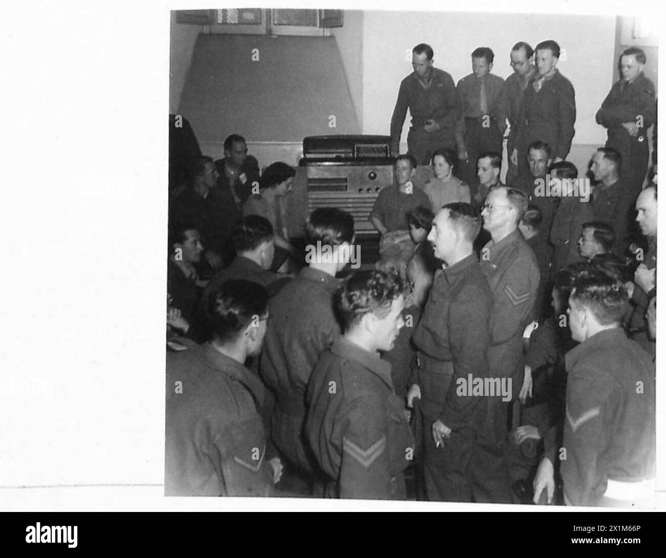 Truppen und Flieger versammeln sich um ein Radio im Gebäude der Katholischen Frauenliga in Rom, um eine Rede von Winston Churchill während des Zweiten Weltkriegs zu hören Stockfoto