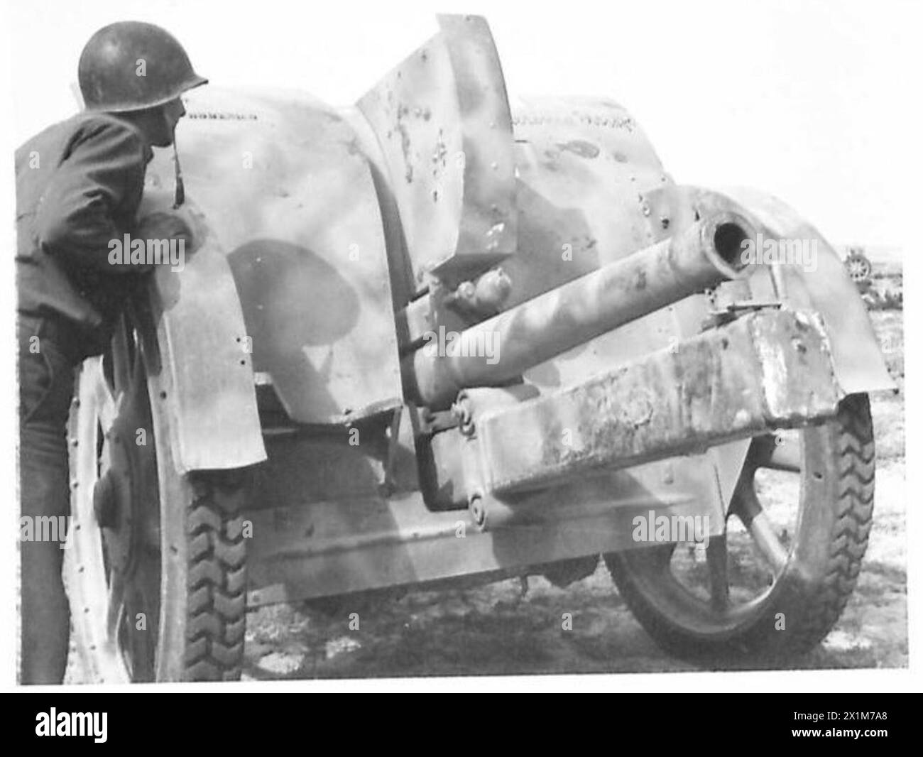 Ein US-amerikanischer Soldat inspiziert ein gefangenes italienisches 75-mm-Feldgewehr bei Gafsa, während die alliierten Truppen in Südeuropa vorrücken. Das Foto zeigt Ausrüstung, die während der Operationen unter Beteiligung der britischen Armee beschlagnahmt wurde. Stockfoto