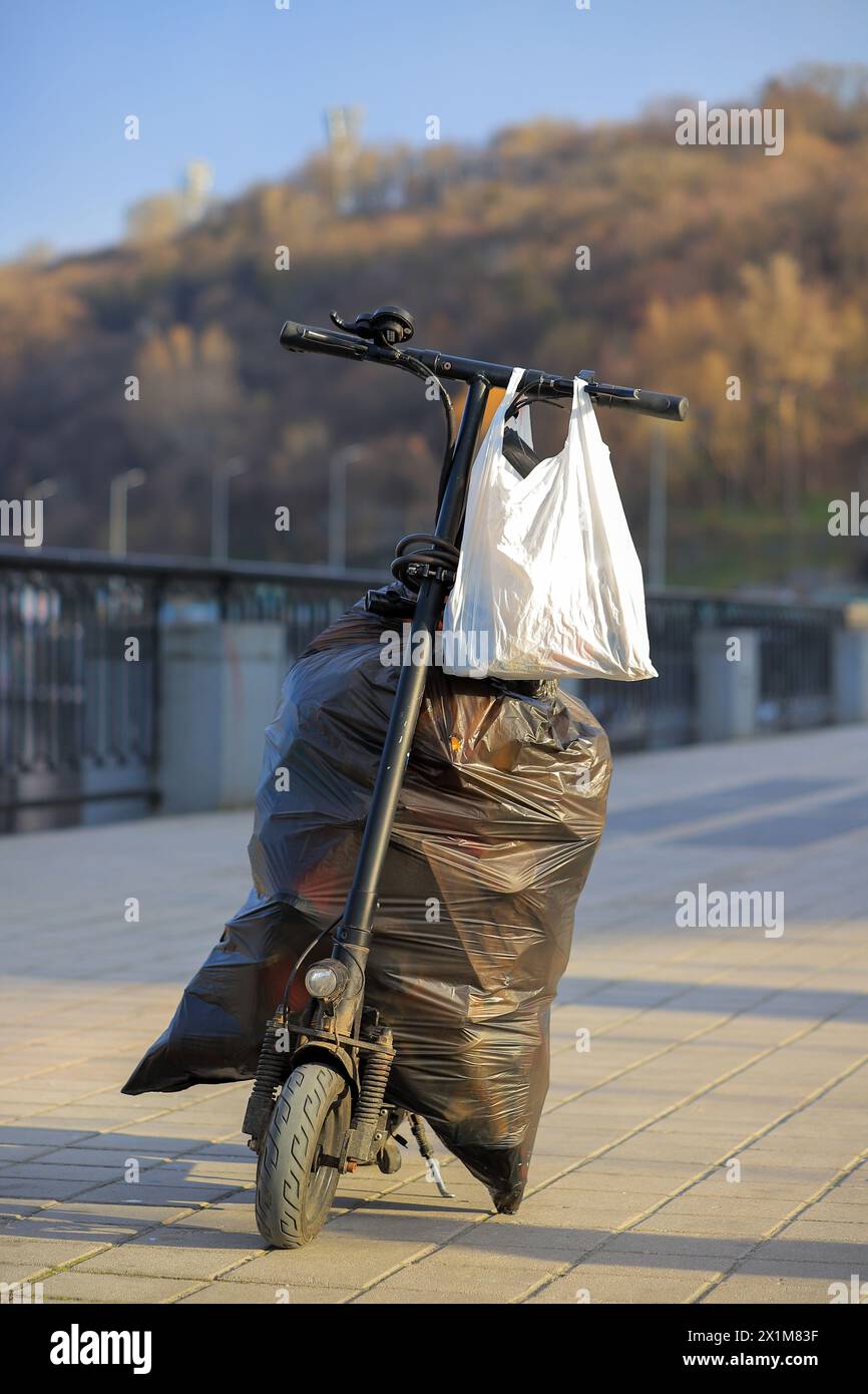 Müllsäcke auf einem Elektroroller auf einer Straße in der Stadt Stockfoto