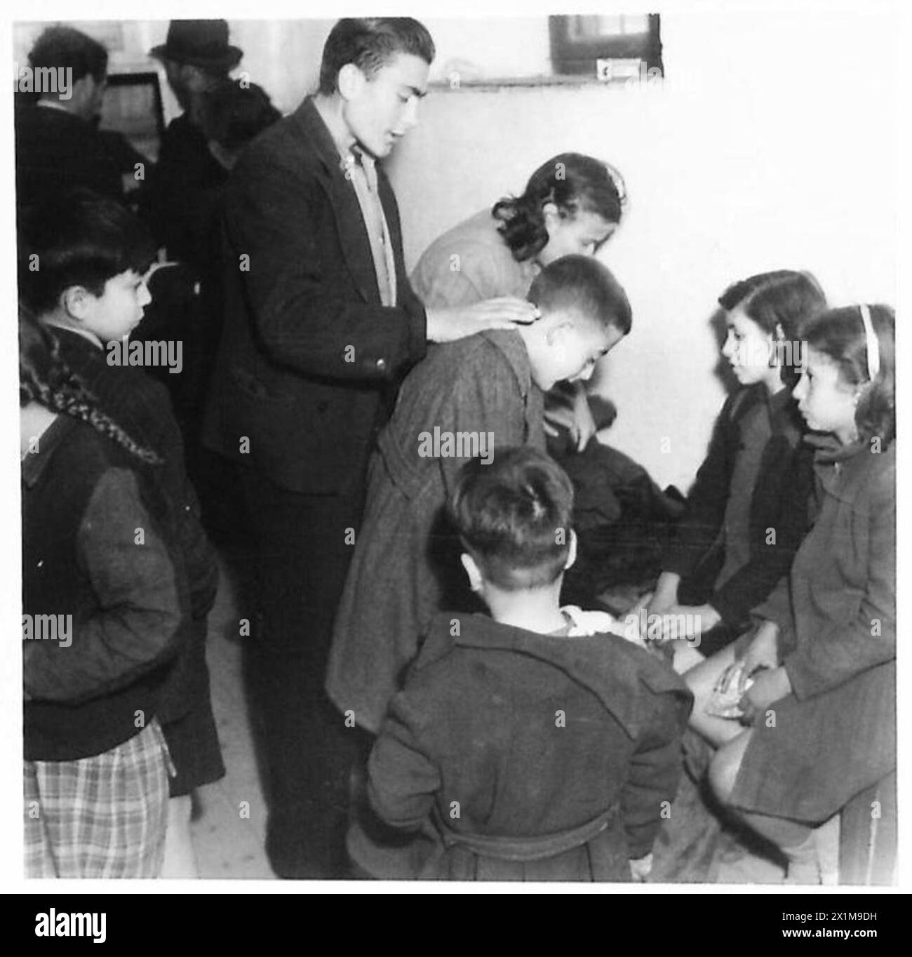 Ein Junge erhält einen Mantel, der vom Roten Kreuz-Bekleidungsvertrieb in Griechenland, der britischen Armee, zur Verfügung gestellt wird. Stockfoto