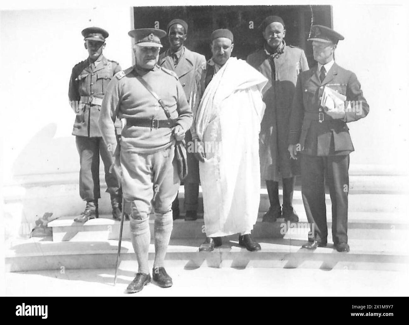 LIEUT. GENERAL SIR HENRY MAITLAND WILSON, DER GOUVERNEUR VON CYRENAIKA, BESUCHT WESTLICHSTE GEBIETE VON CYRENAIKA, LIBYEN - LIEUT. General Sir Henry Maitland Wilson, mit einigen einheimischen Häuptern eines Dorfes nach einem Gespräch. Mit dem General ist Major Burges Watson, politischer Offizier der Western Cyrenaica (in R.A.F. Uniform), British Army Stockfoto