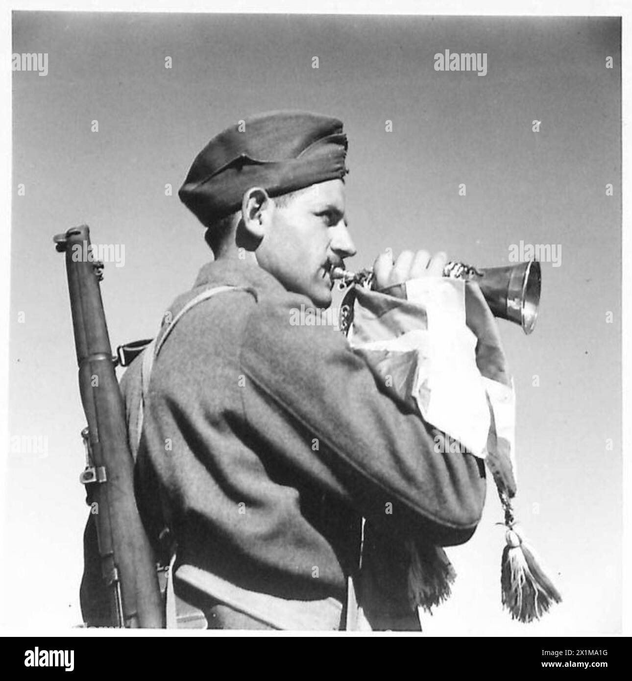 General E. Tzanakakis und Prinz Peter von Griechenland besuchen ein Trainingslager, wo ein Bugler ihre Ankunft ankündigt, die griechische Armee, beobachtet von der britischen Armee. Stockfoto