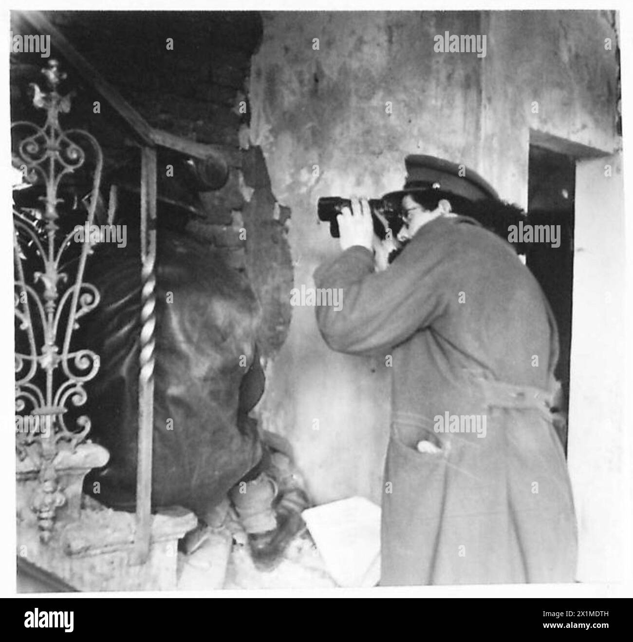 Major Clark Kennedy von der D Squadron, 12 Lancers, beobachtet einen Bren-Schützen, während Shermans einen feindlichen Stützpunkt in den Überresten eines Dorfbildhauses, der achten Armee, der britischen Armee, beschießen. Stockfoto