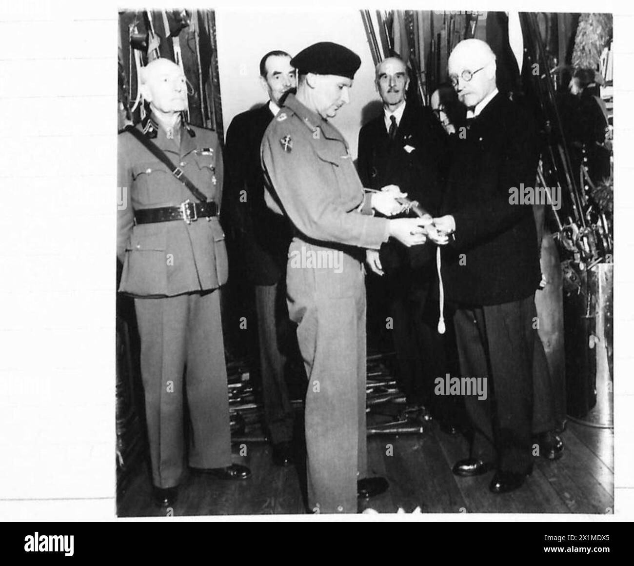 EXKLUSIV – in Anerkennung seiner Verdienste um die Befreiung Belgiens erhielt Feldmarschall Sir Bernard Montgomery, Oberbefehlshaber der 21. Armeegruppe, ein historisches belgisches Schwert. Es war das Schwert des ersten Etat-Majors der belgischen Armee. Auf der Scheide waren die Worte: „AU LIBERATEUR DE BRUXELLES LE 3 SEPTEMBER 1944, SES AMIS RECONNAISSANTS. OFFERT PAR COMTE DE RIBANCOURT, LES MEMBRES DE L'ASSOCIATION DE MALTE, ET LES MEMBRES DU CERCLE DU PARC BRUXELLES." Das Foto zeigt Comte de Rinancourt, der dem Feldmarschall, der britischen Armee, der 21. Armeegruppe, das Schwert vorstellt Stockfoto