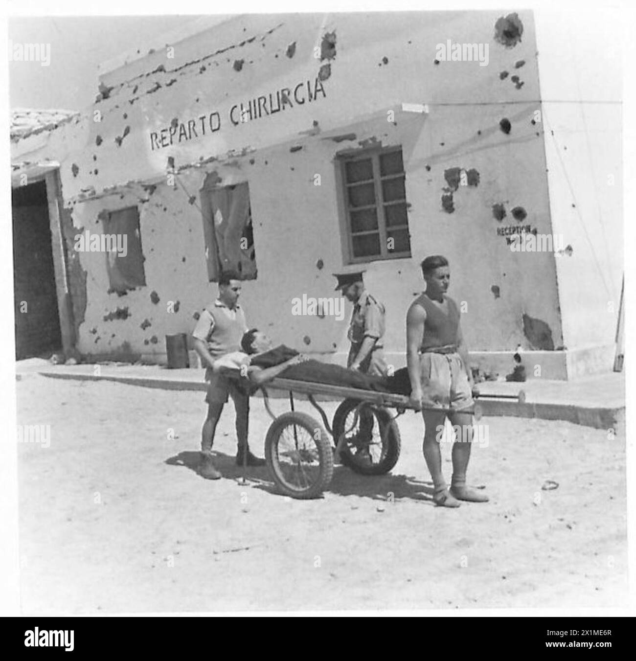 BILDER AUS TOBRUK : LEBEN IN Einem KRANKENHAUS IN TOBRUK - der Krankenhauspadre hält an und plaudert mit einem verletzten Soldaten, der von italienischen Gefangenen, die als Bahrenträger fungieren, zu einer der Stationen gefahren wird und andere seltsame Aufgaben über das Krankenhaus, die britische Armee, erledigt Stockfoto