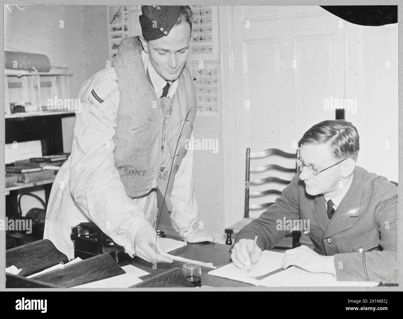 Der Kapitän eines kurzen Sunderland-Patrouillenflugzeugs meldet sich dem Geheimdienstoffizier, bevor er tägliche Patrouillendienste durchführt, um die Seeverkehrsoperationen der RAF zu veranschaulichen. Stockfoto