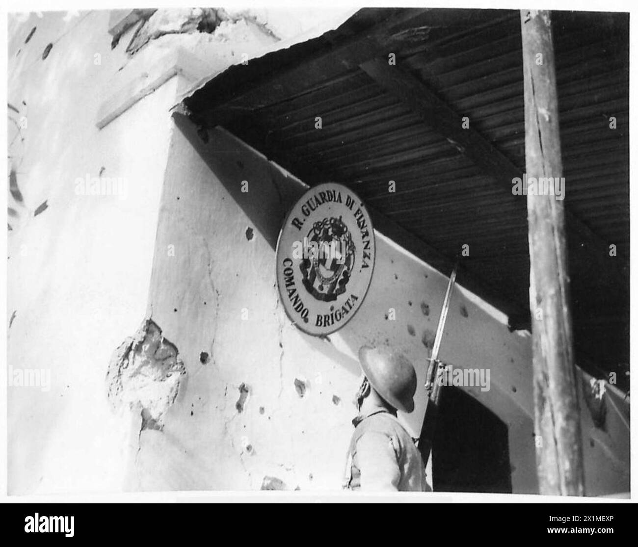 Ein britischer Soldat inspiziert ein Schild vor dem Hauptquartier der italienischen Brigade in Bardia, British Army. Stockfoto