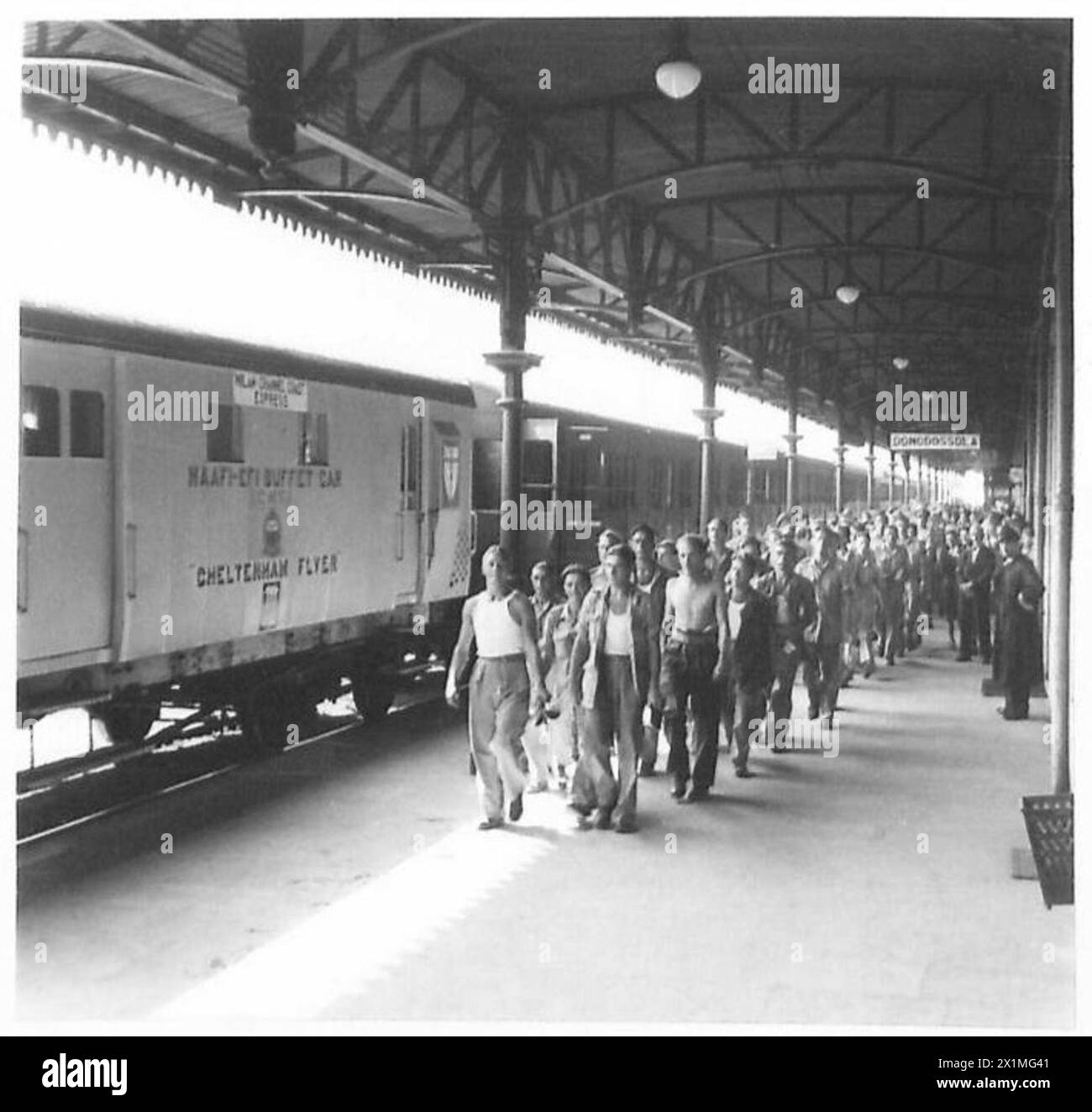 Am Bahnhof Domodossola kommt der dritte Zug aus Mailand an; Truppen marschieren in den Speisesaal, während die Dampflok für die kurze Fahrt durch die Schweiz durch eine Elektrolok ersetzt wird. Stockfoto