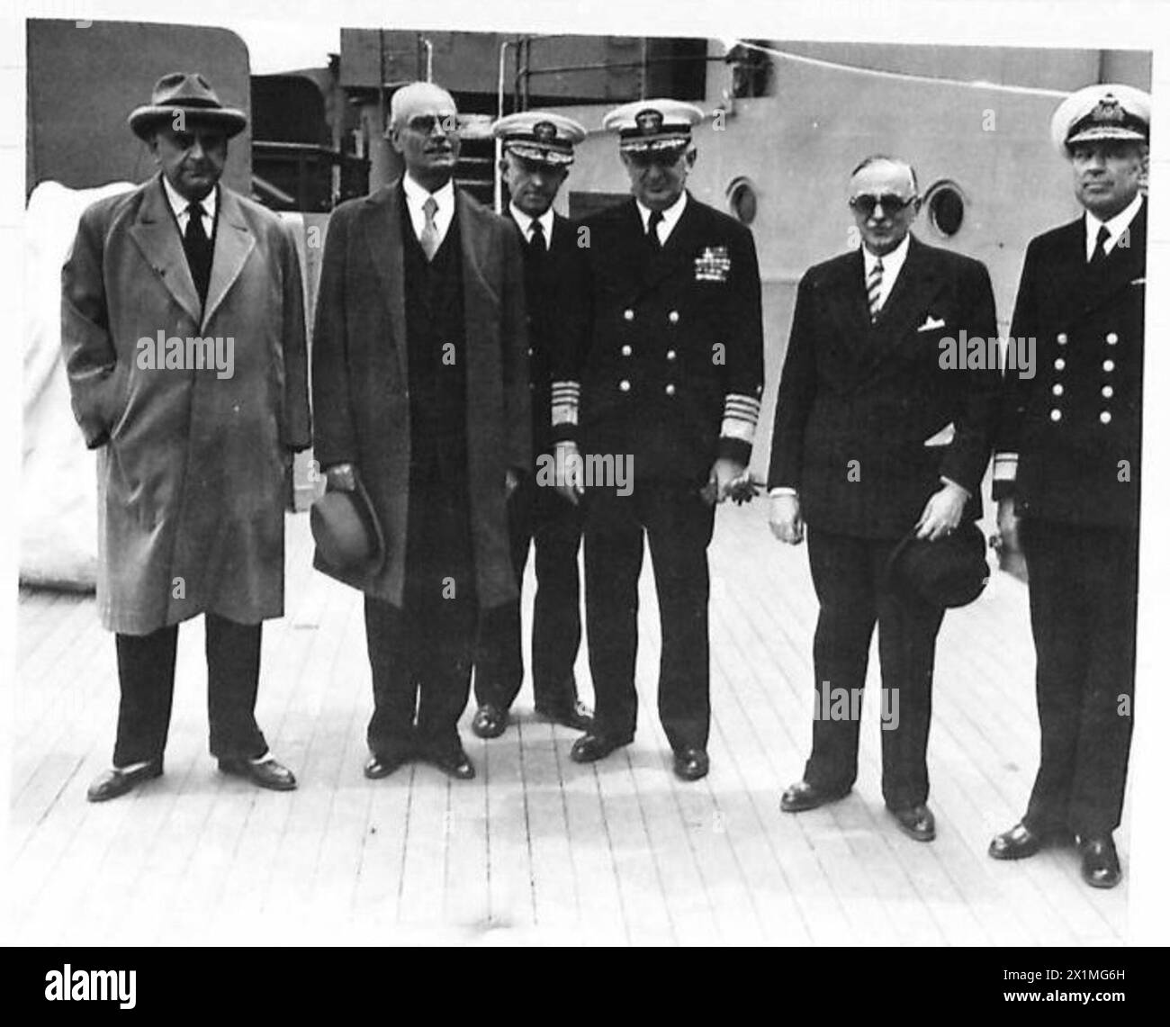 USA 'MISSOURI' BEREIST DAS MITTELMEER - Admiral Hewitt mit dem neuen griechischen Premierminister Poulitsis zu seiner Linken, steht mit Herrn Tsaldaris (Außenminister) (mit Trilby-Hut) und Herrn Mavro Michalis (Verteidigungsminister), hinter der "Kapitulation"-Plakette im Vordergrund. Mr. Pulitsis (griechischer Premierminister) blickt staunend auf die gewaltige Struktur des Schlachtschiffs Missouri, der britischen Armee Stockfoto