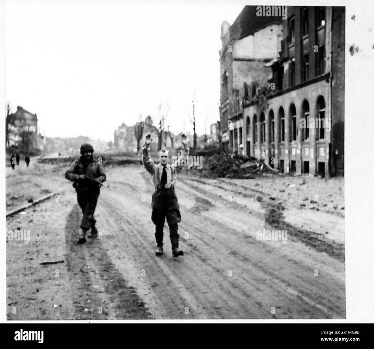 KÖLN - einer der Scharfschützen, die von den zurückziehenden Deutschen zurückgelassen werden, wird von einem amerikanischen Soldaten, einer britischen Armee, einer 21. Armeegruppe aus seinem Versteck gebracht Stockfoto