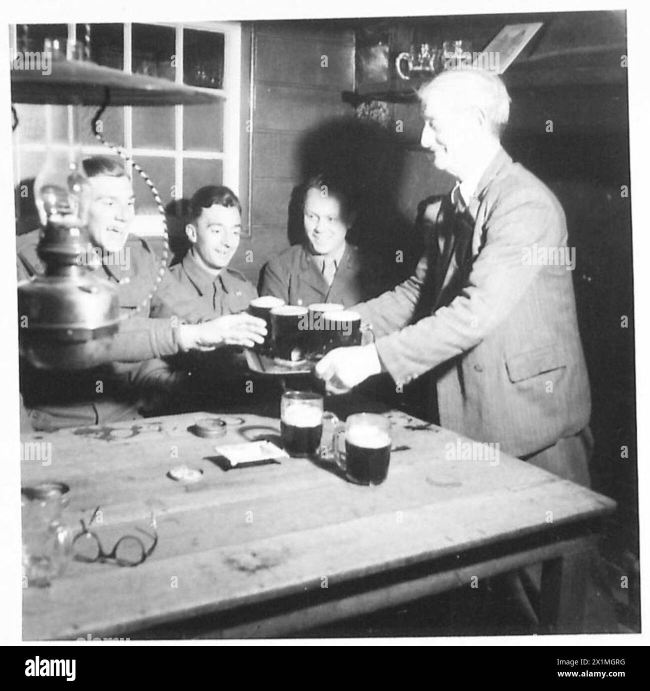 Charles Davis, ein Veteran des vorherigen Krieges, begrüßt britische und amerikanische Soldaten in seinem Pub im Dorf und serviert Getränke für Privates Campin, Bennett und Corporal Arnold Nordby von der amerikanischen Armee. Stockfoto Charles Davis, ein Veteran des vorherigen Krieges, begrüßt britische und amerikanische Soldaten in seinem Pub im Dorf und serviert Getränke für Privates Campin, Bennett und Corporal Arnold Nordby von der amerikanischen Armee. Stockfoto