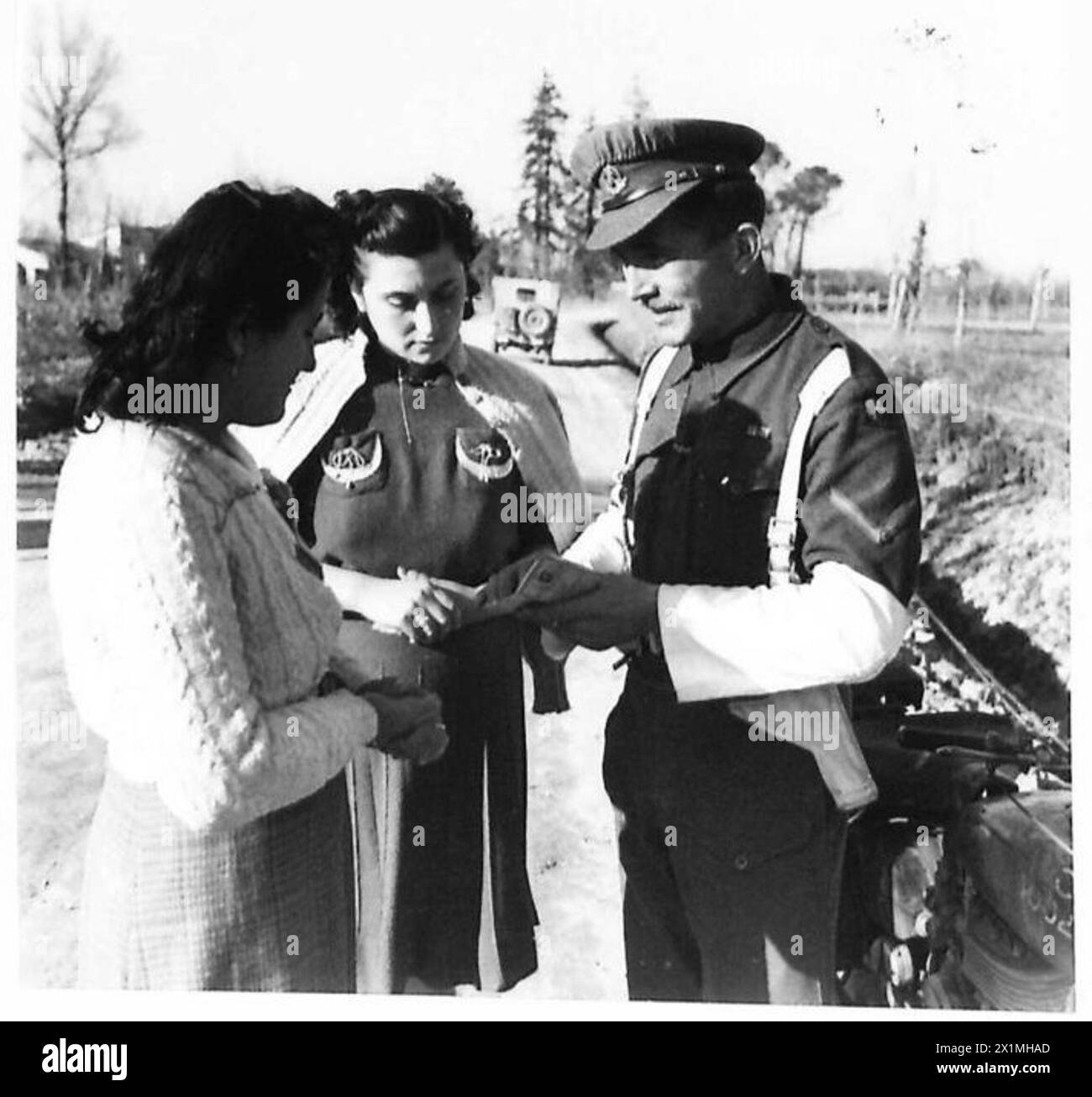 L/CPL. John Johnson von der britischen 8. Armee kontrolliert nach Einsätzen in Nordafrika, Sizilien und Italien seit 1943 zwei italienische Zivilisten in den vordersten Gebieten. Stockfoto