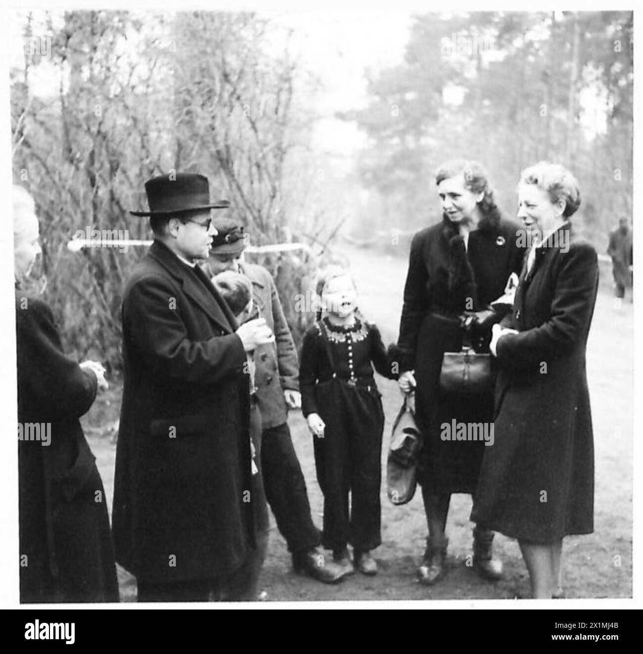 Ein Priester spricht mit deutschen Zivilisten unter britischer Militärverwaltung, British Army, 21st Army Group, während der Besatzungsaufgaben. Stockfoto