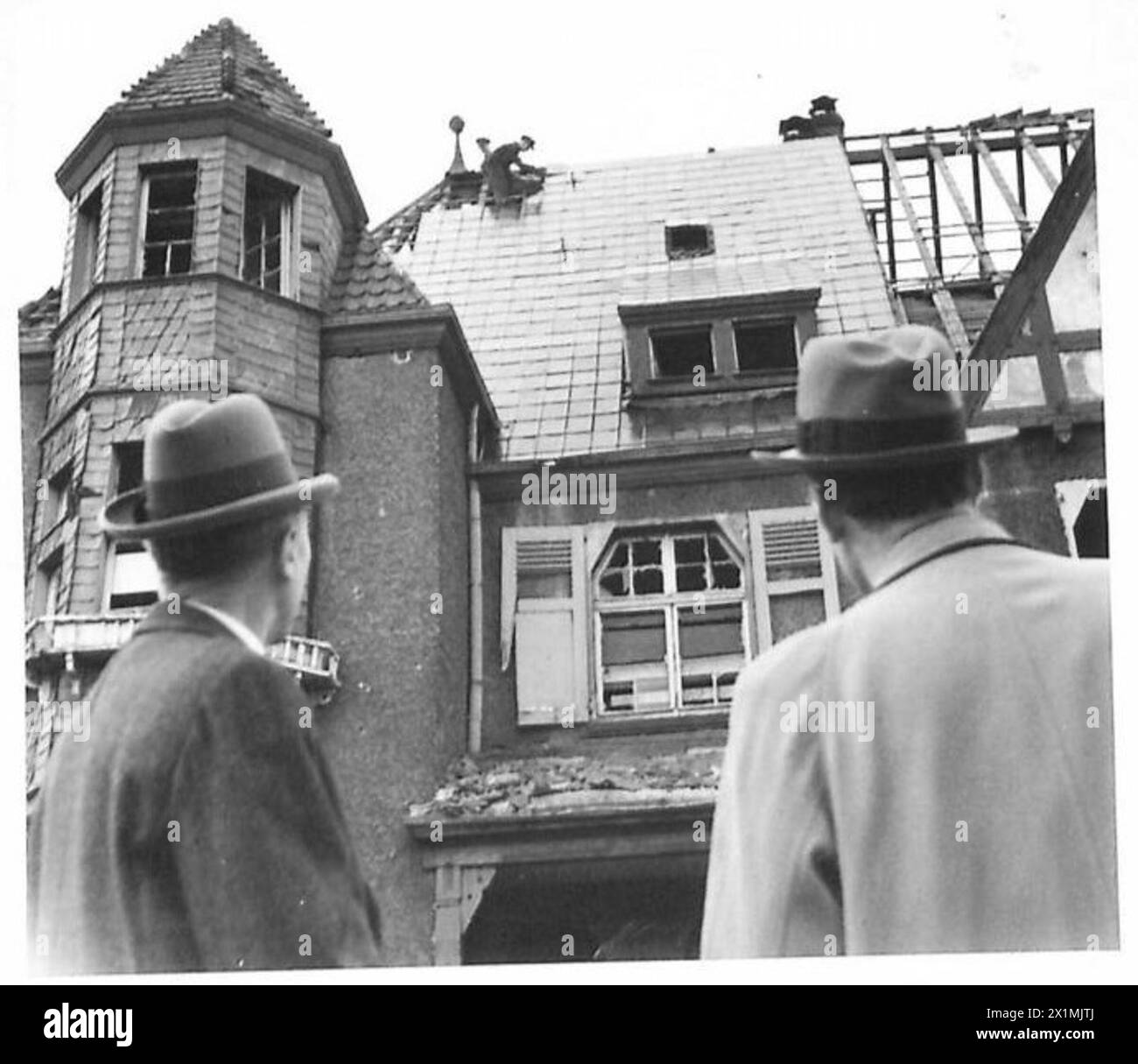 Der Oberbürgermeister beobachtet die Reparatur eines Hauses mit Metallfliesen während der Umstrukturierung der Zivilverwaltung in Köln, unter der Britischen Rheinarmee. Stockfoto