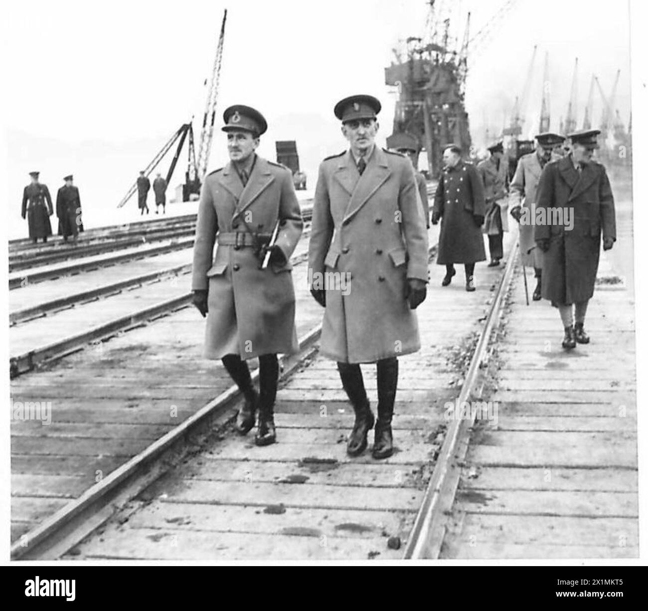 Der Oberbefehlshaber der Home Forces inspiziert einen Abschnitt eines Hafens in Schottland, begleitet von Colonel C. A. Bailey, der von britischen Armeepersonal beobachtet wird. Stockfoto