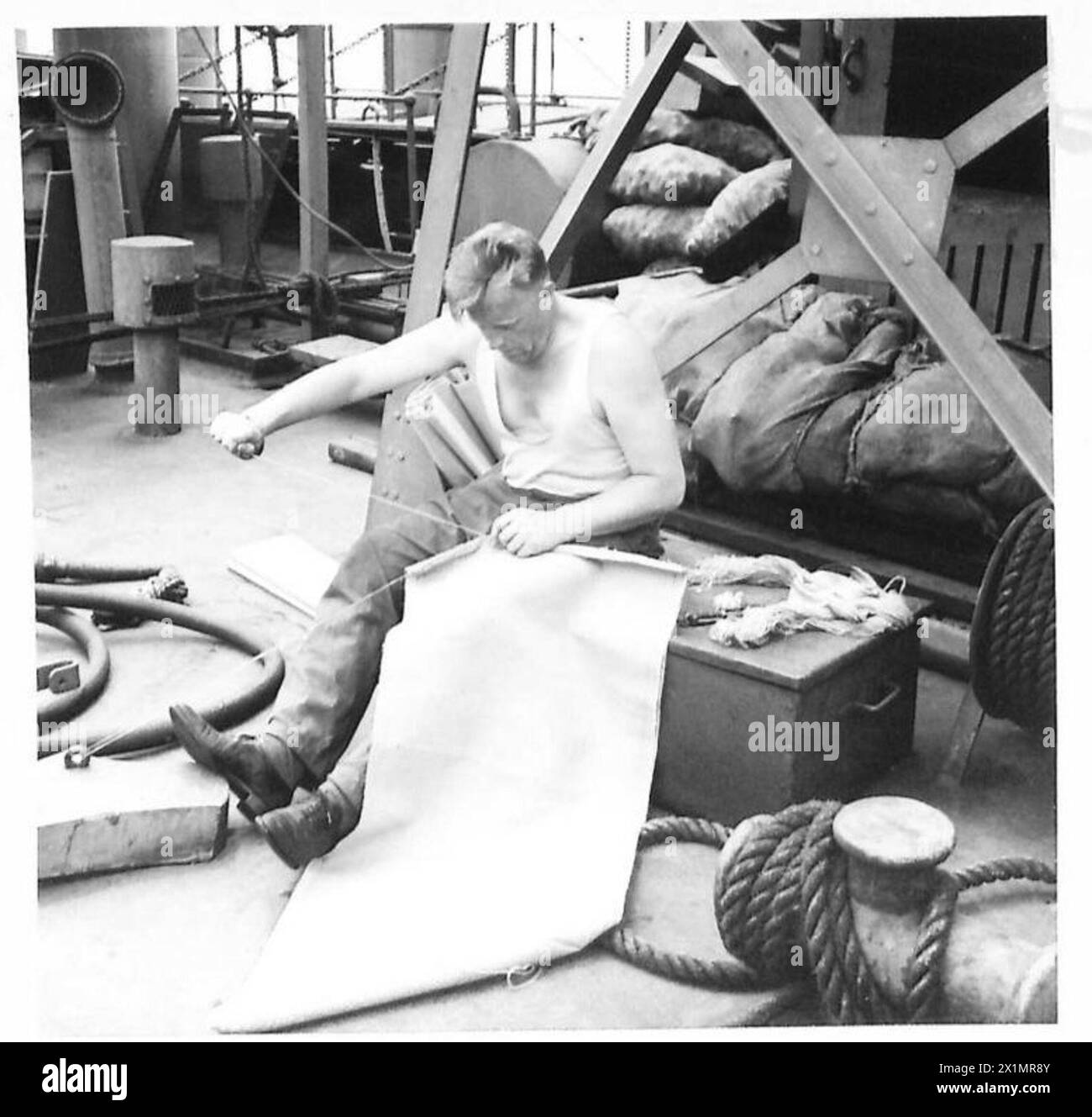 J. Kay von den Shetland-Inseln führt Leinwandnähte an Deck eines Konvoyschiffs der britischen Armee durch, das nach Afrika fährt, und demonstriert die Wartungsaufgaben an Bord. Stockfoto