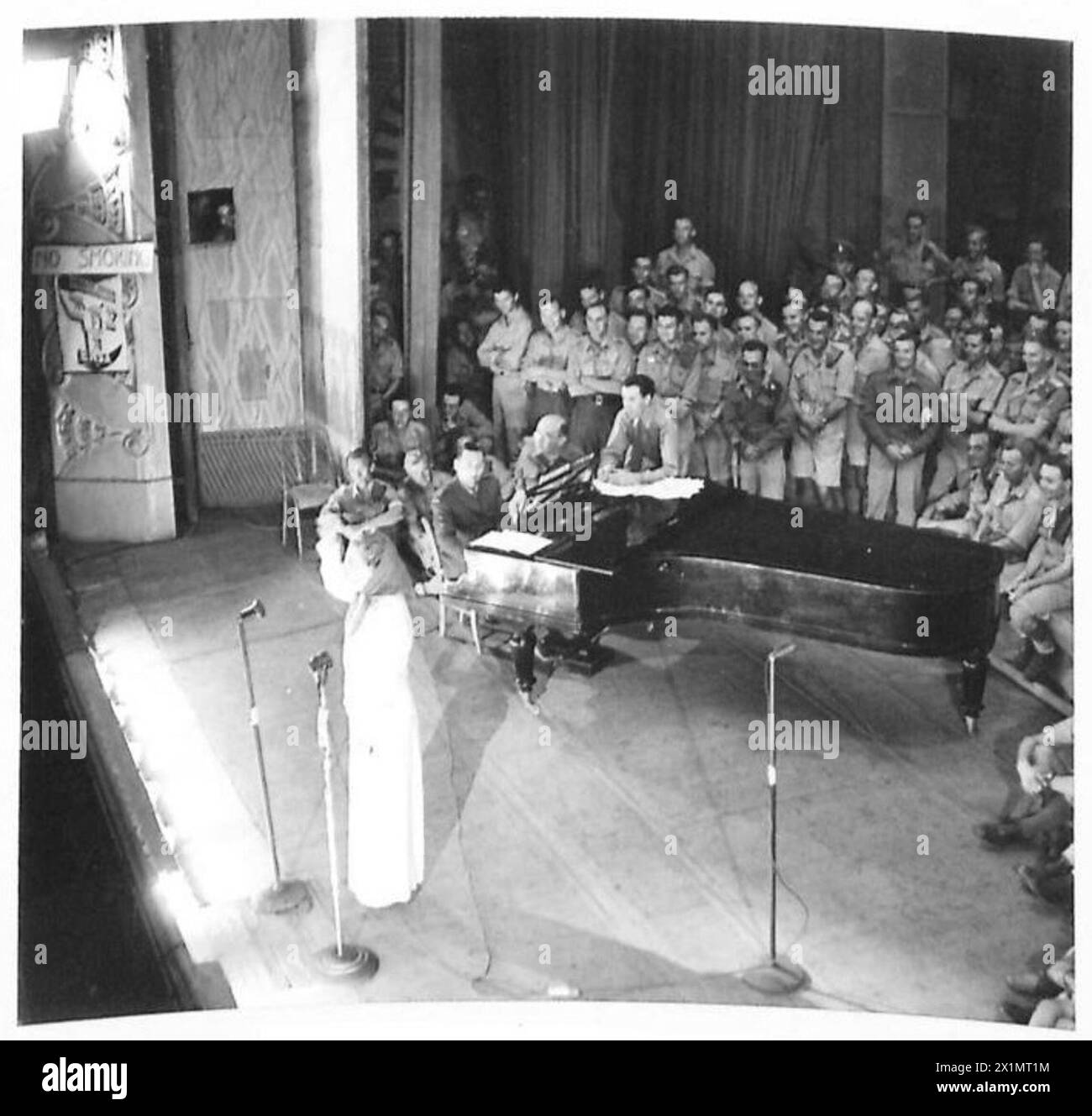 Gracie Fields tritt in Nordafrika auf, wobei ein Publikum das Auditorium und die Bühne während einer Sendung füllt, die für den Rundfunk aufgenommen wurde, British Army Present. Stockfoto Gracie Fields tritt in Nordafrika auf, wobei ein Publikum das Auditorium und die Bühne während einer Sendung füllt, die für den Rundfunk aufgenommen wurde, British Army Present. Stockfoto
