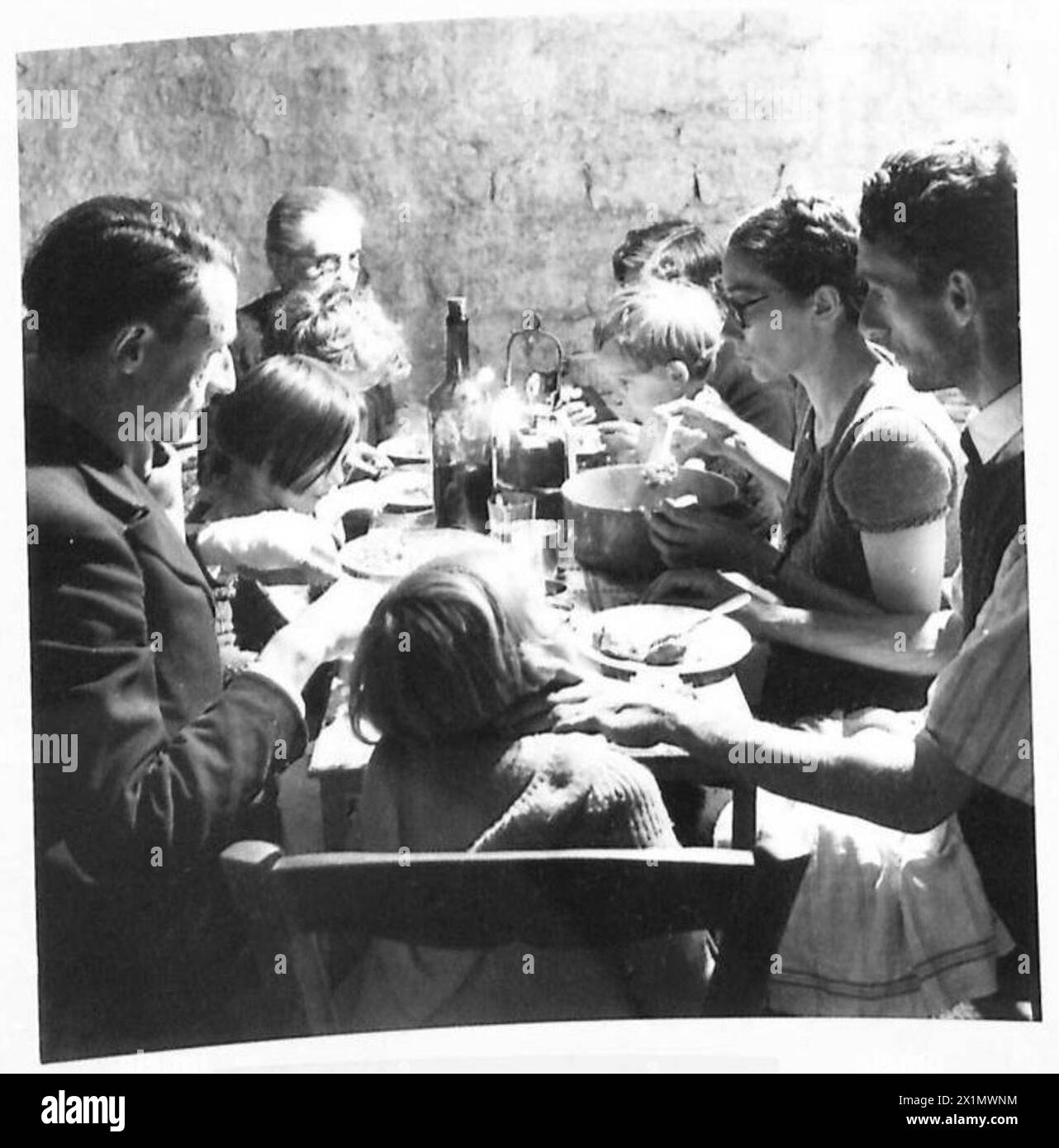Familien teilen ihre Mahlzeiten mit Kerze und Öllampe in einem unterirdischen Unterschlupf in Caen, unter der Aufsicht der britischen Armee, 21st Army Group. Stockfoto